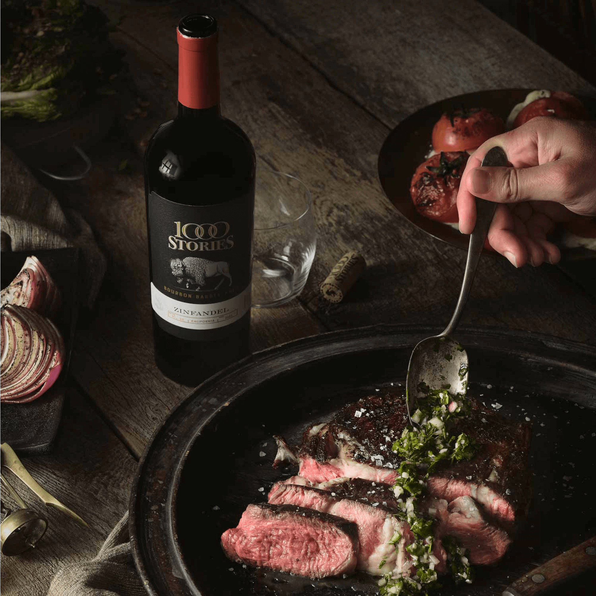 A bottle of 1000 Stories Zinfandel next to a plate of steak, garnished with herbs, showcasing a perfect pairing.