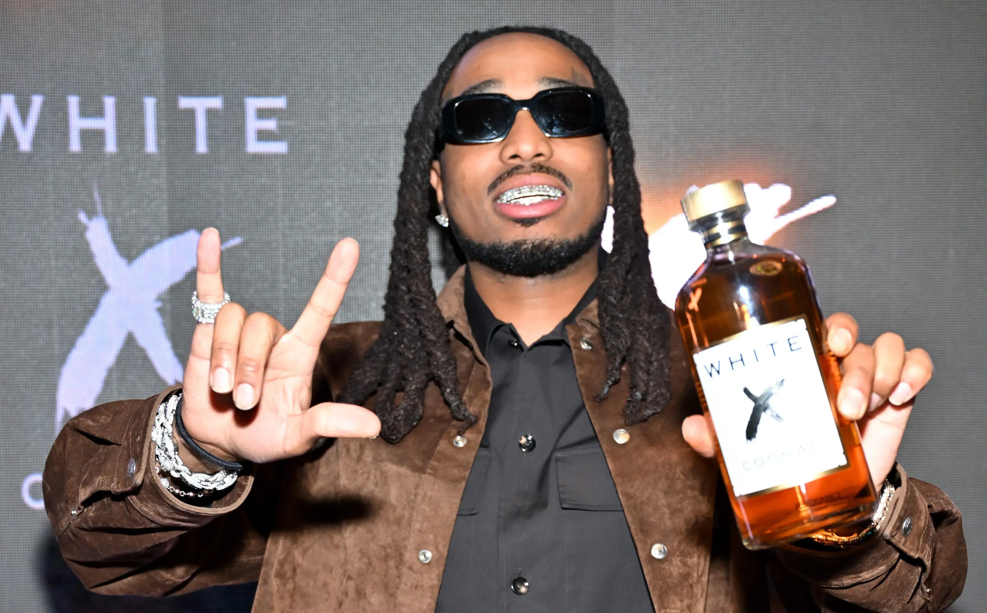 Quavo posing with White X Cognac bottle, promoting the modern cognac brand at a launch event.