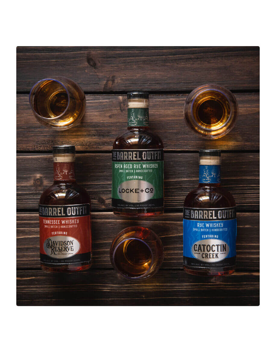 The Barrel Outfit Variety 3 Pack featuring three 200mL whiskey bottles with tasting glasses on a wooden table.