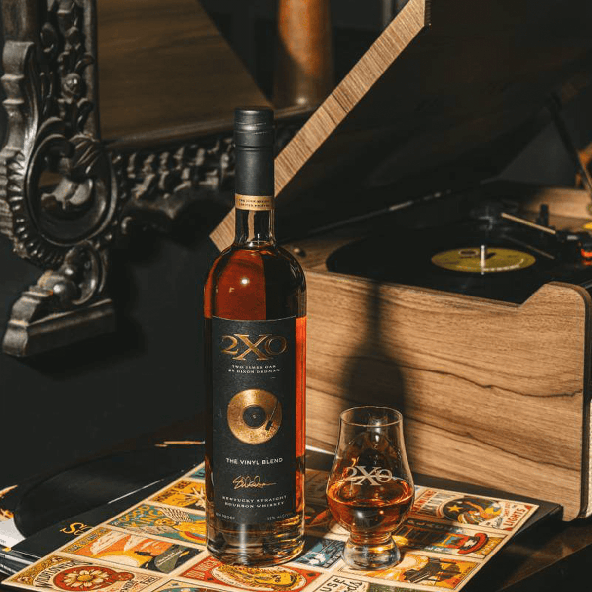 Bottle of 2XO The Vinyl Blend Bourbon next to a vinyl record player and a glass of bourbon.