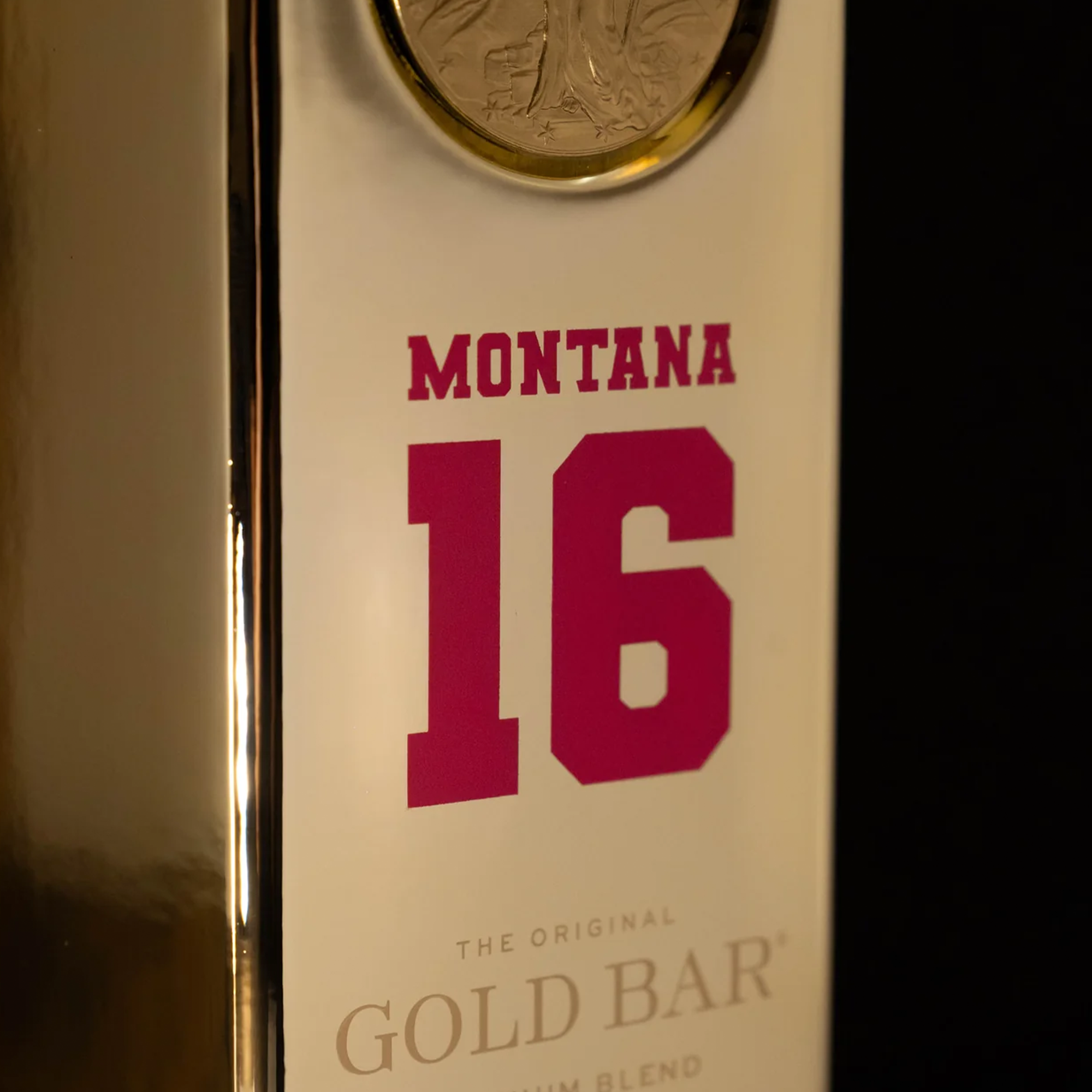Close-up of Gold Bar Joe Montana Blend whiskey bottle featuring the number 16 and Montana's name in bold red.