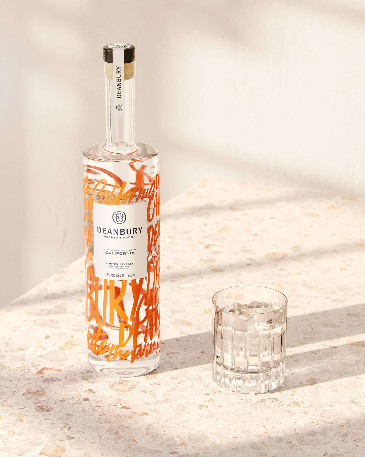 Bottle of Deanbury Premium Vodka on marble surface with a glass, highlighting its unique design and smoothness.