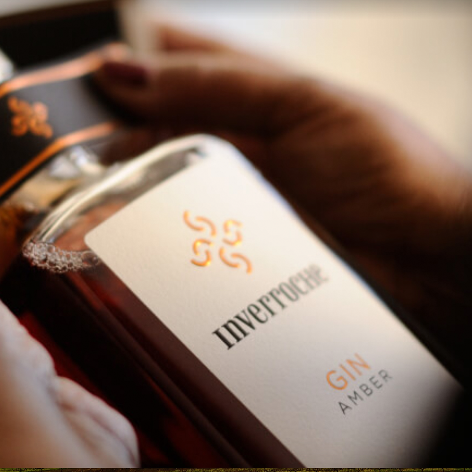 Inverroche Amber Craft Gin bottle showcasing rich amber color and fynbos infusion, held by a hand.