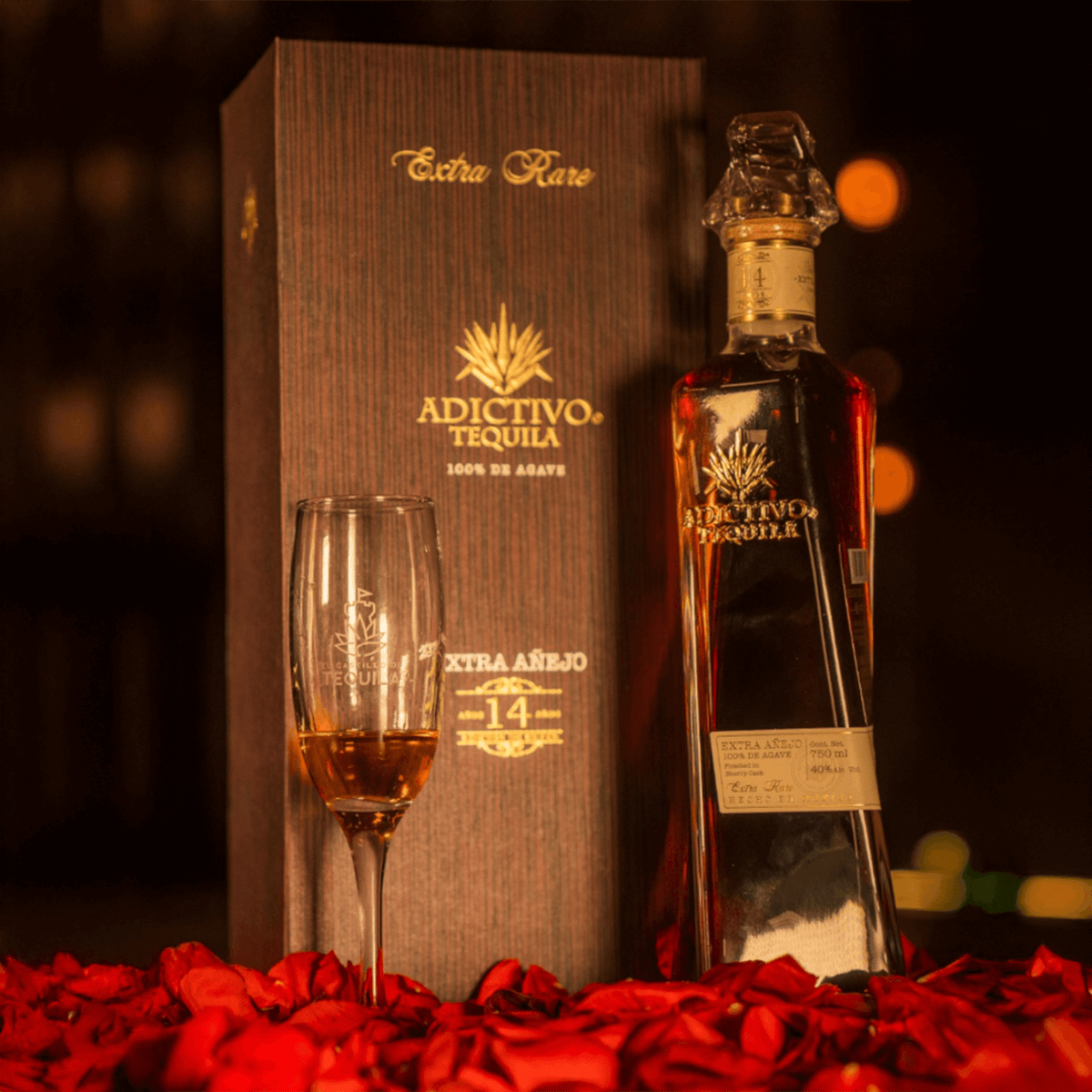 Adictivo Extra Rare 14 Year Extra Añejo Tequila bottle and glass, elegantly displayed with rose petals.