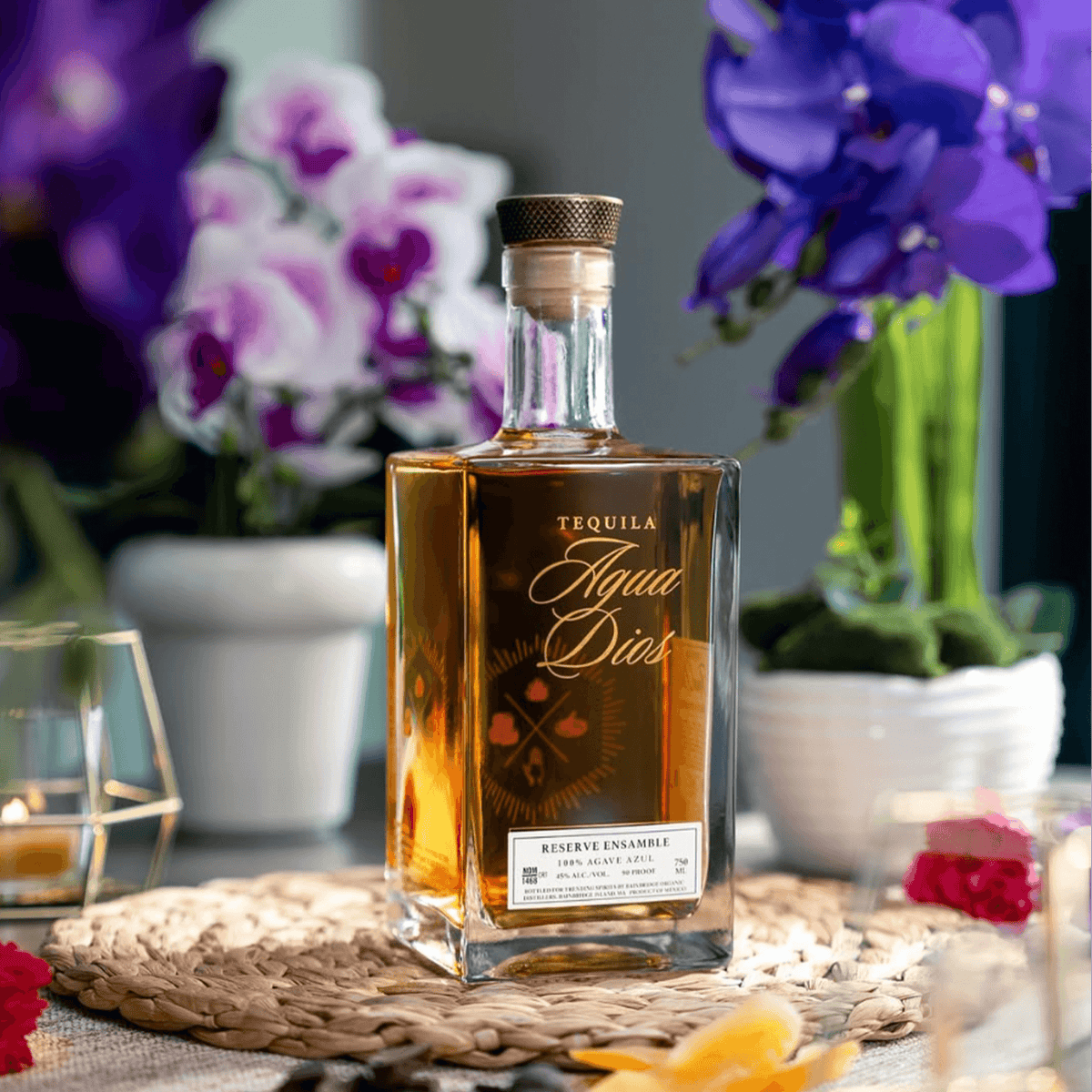 AguaDios 15 Year Reserve Ensemble Tequila bottle with floral background and decorative elements.