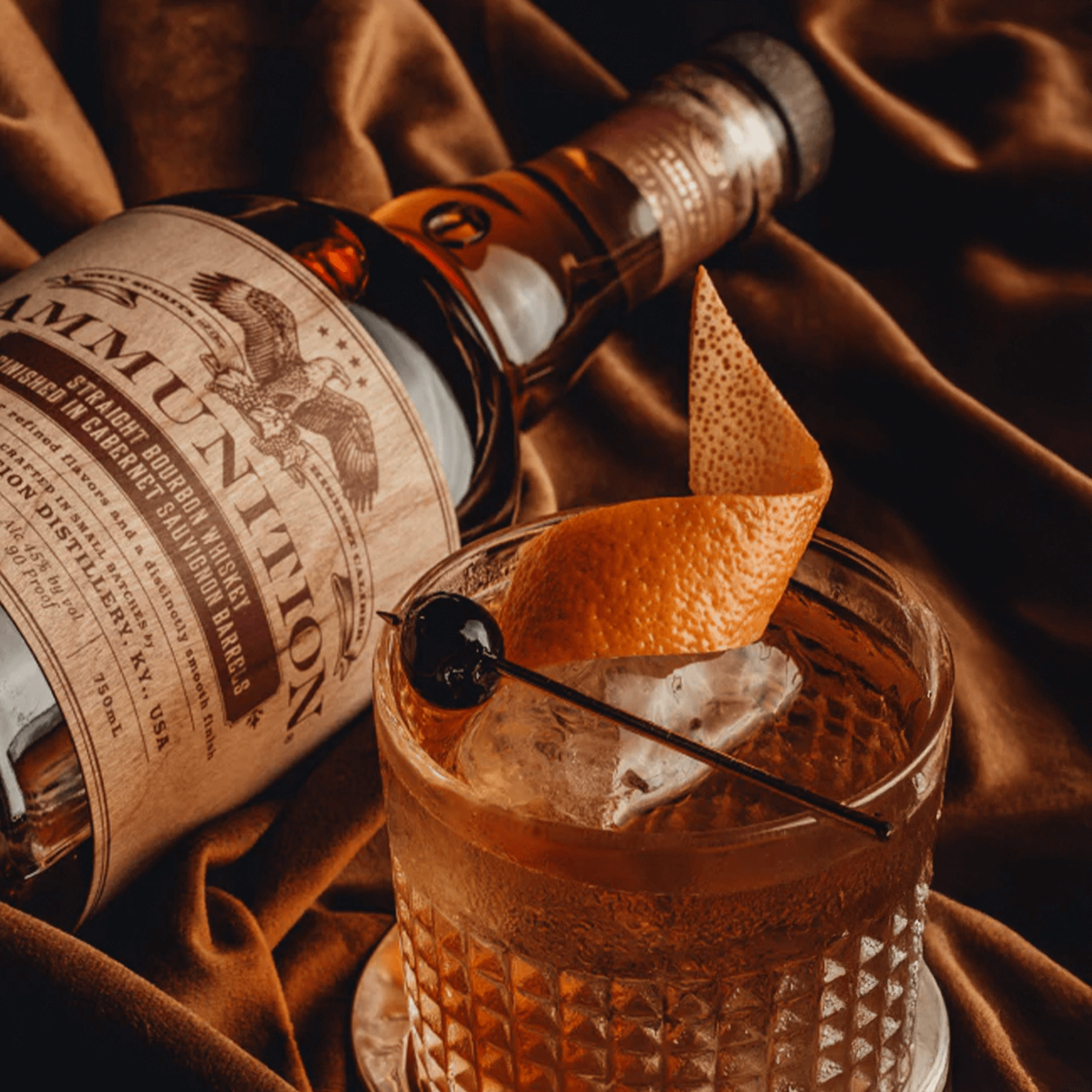 Ammunition Straight Bourbon Whiskey bottle beside an elegantly garnished cocktail on a velvet background.