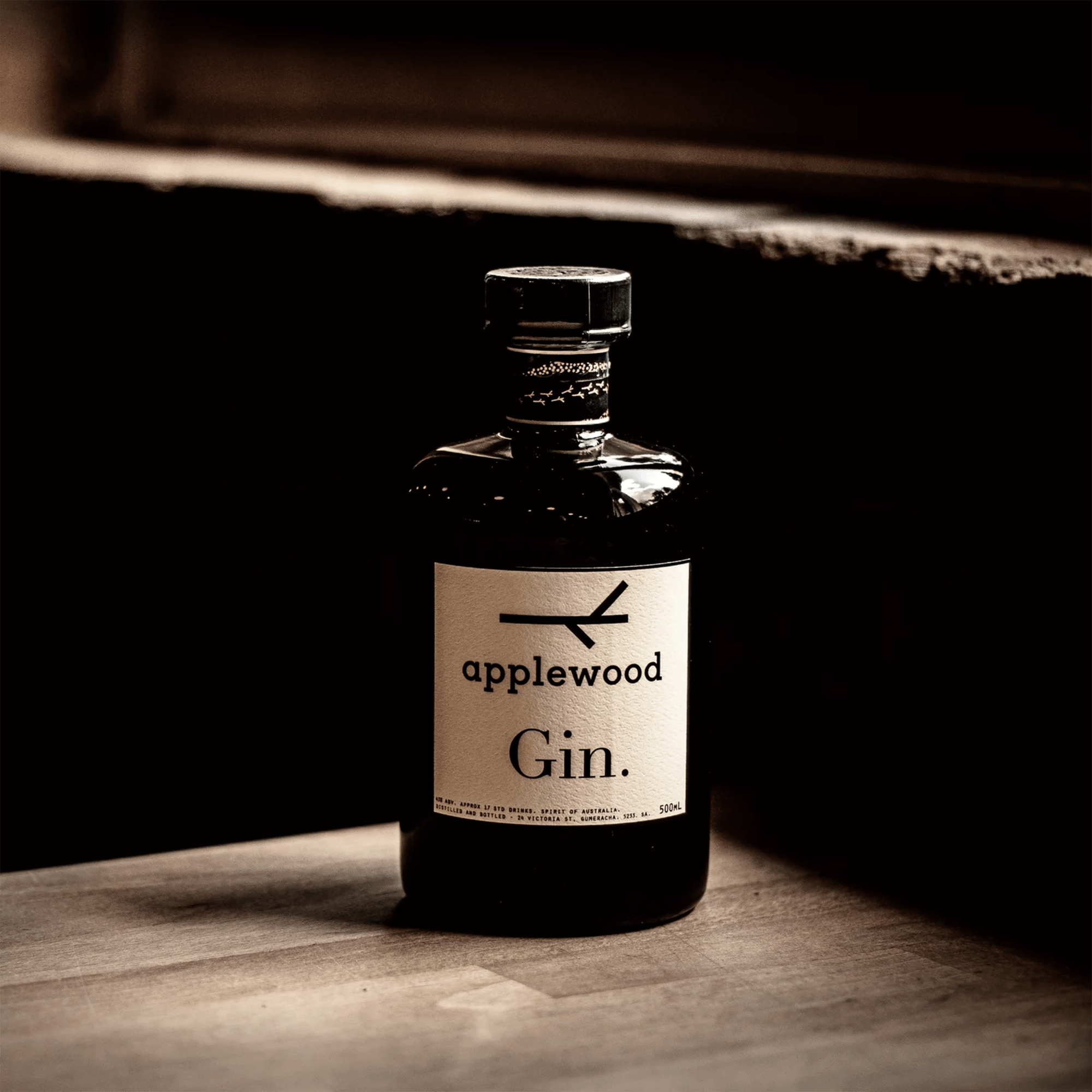 Bottle of Applewood Australian Gin, featuring a minimalist design, resting on a wooden surface.