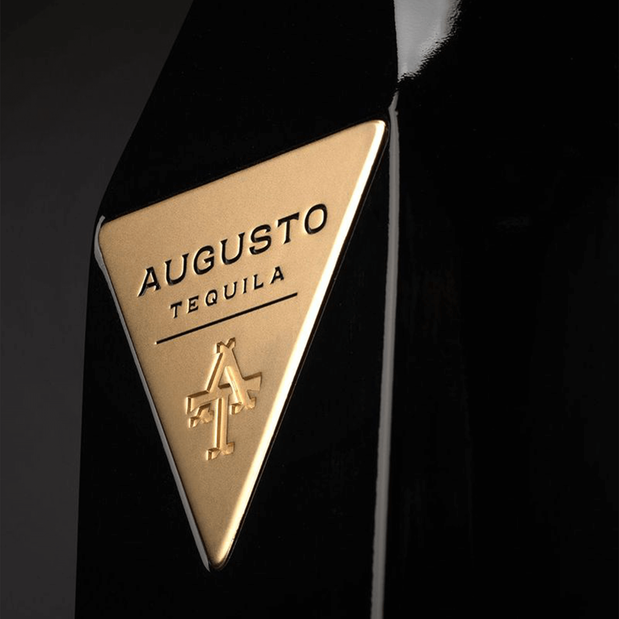 Close-up of the AUGUSTO Tequila logo on a black bottle, highlighting the premium branding.