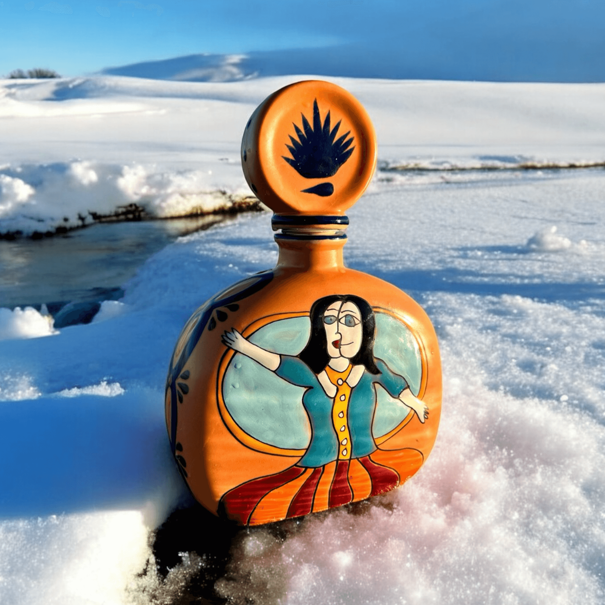 Hand-painted Añejo Orange Tequila bottle from the Azulejos Masterpiece Collection in a snowy landscape.