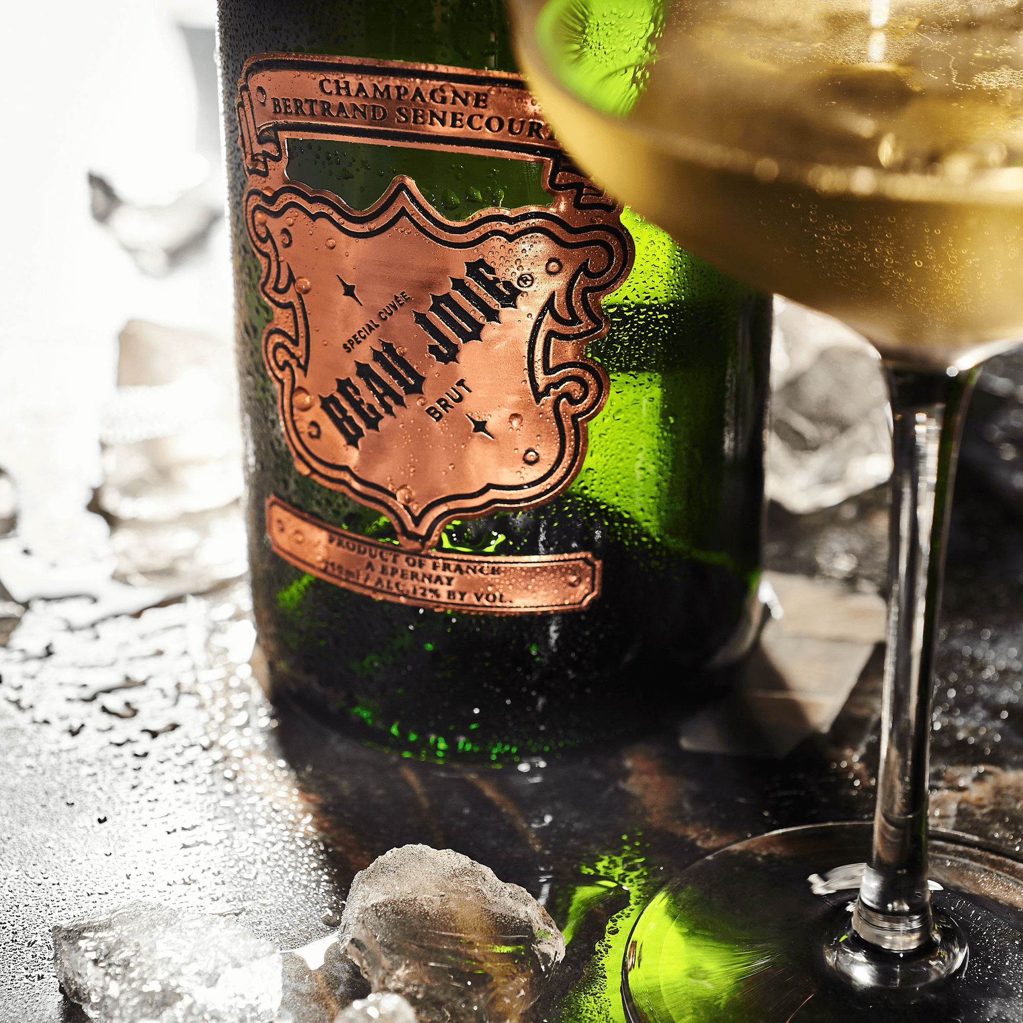 Beau Joie Brut Champagne bottle with a filled glass, surrounded by ice, showcasing its elegant design and clarity.