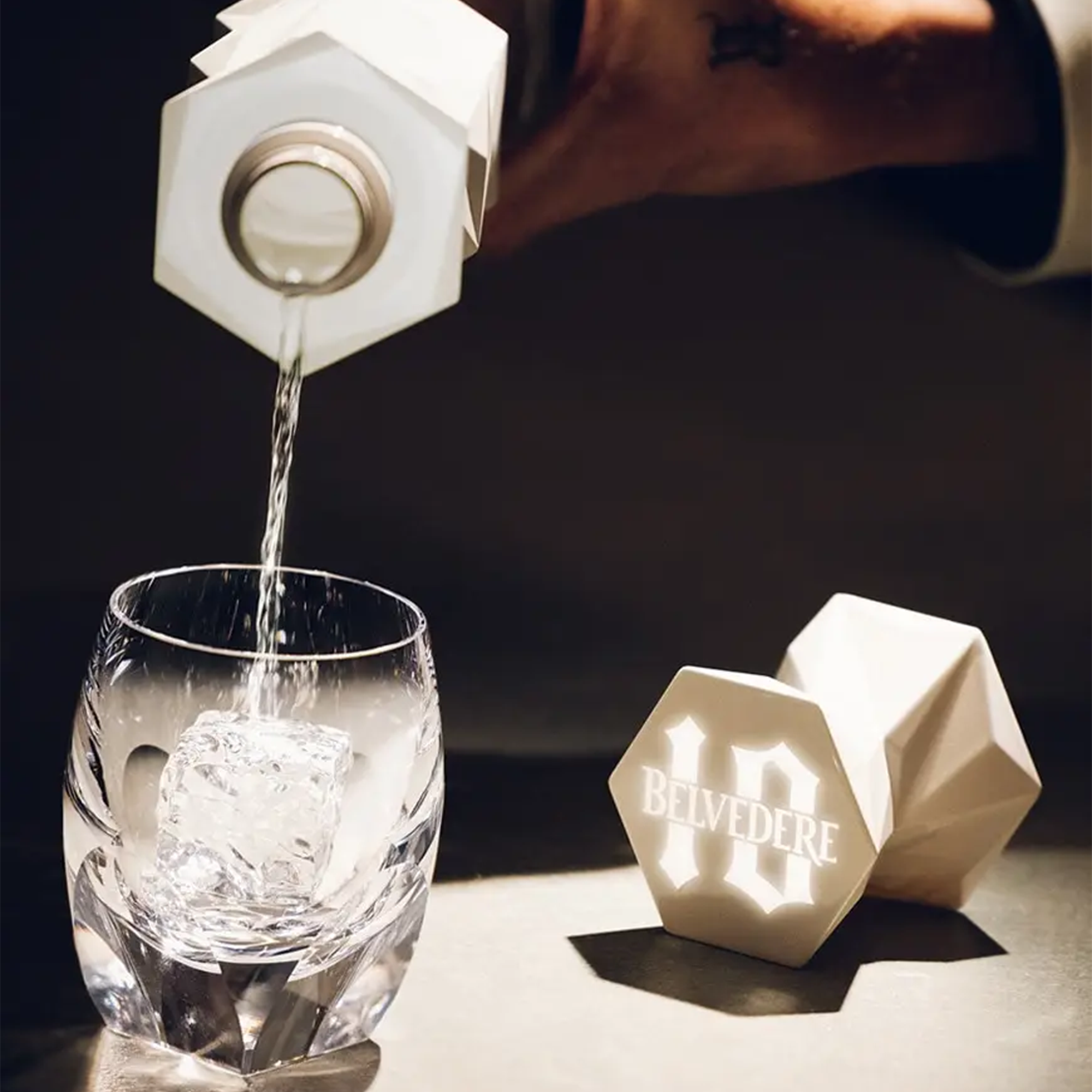 Pouring Belvedere 10 luxury vodka into a glass with ice, showcasing its elegant packaging.