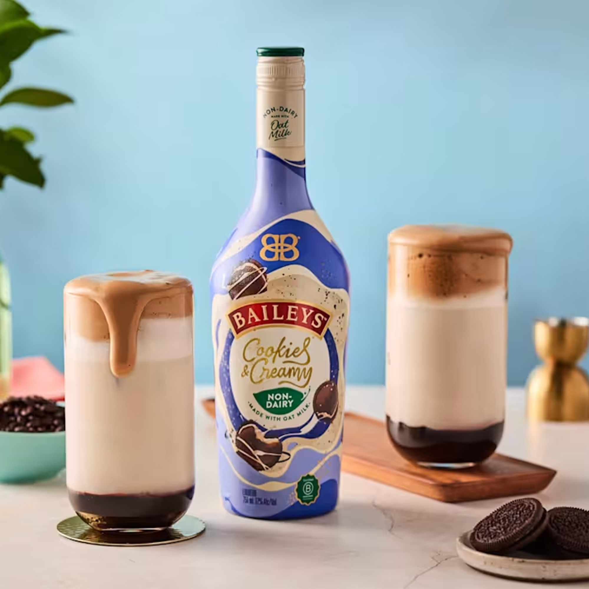 Baileys Cookies & Creamy Non-Dairy Liqueur bottle surrounded by delicious drinks topped with foam and cookies.