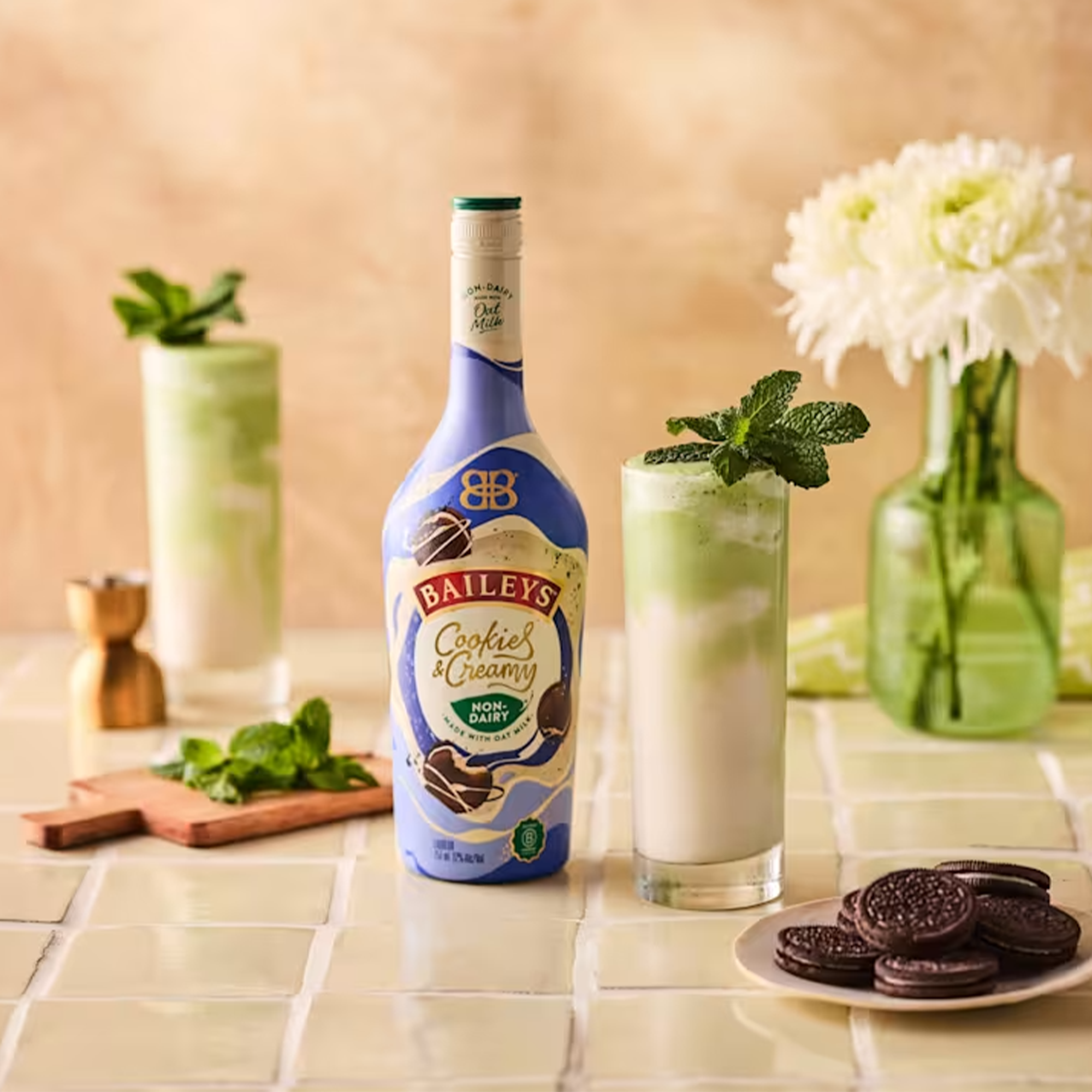 Baileys Cookies & Creamy Non-Dairy Liqueur with mint and glasses on a table, highlighting oat milk flavors.