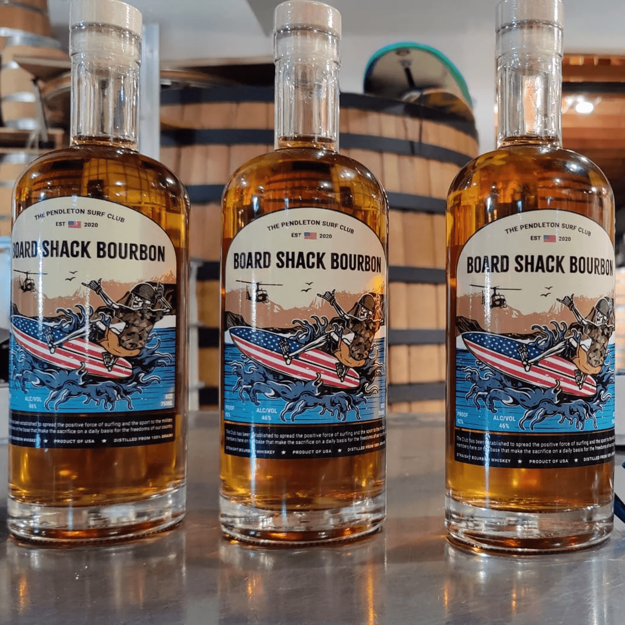 Board Shack Bourbon bottles displayed, promoting the Camp Pendleton Surf Club's mission and community spirit.