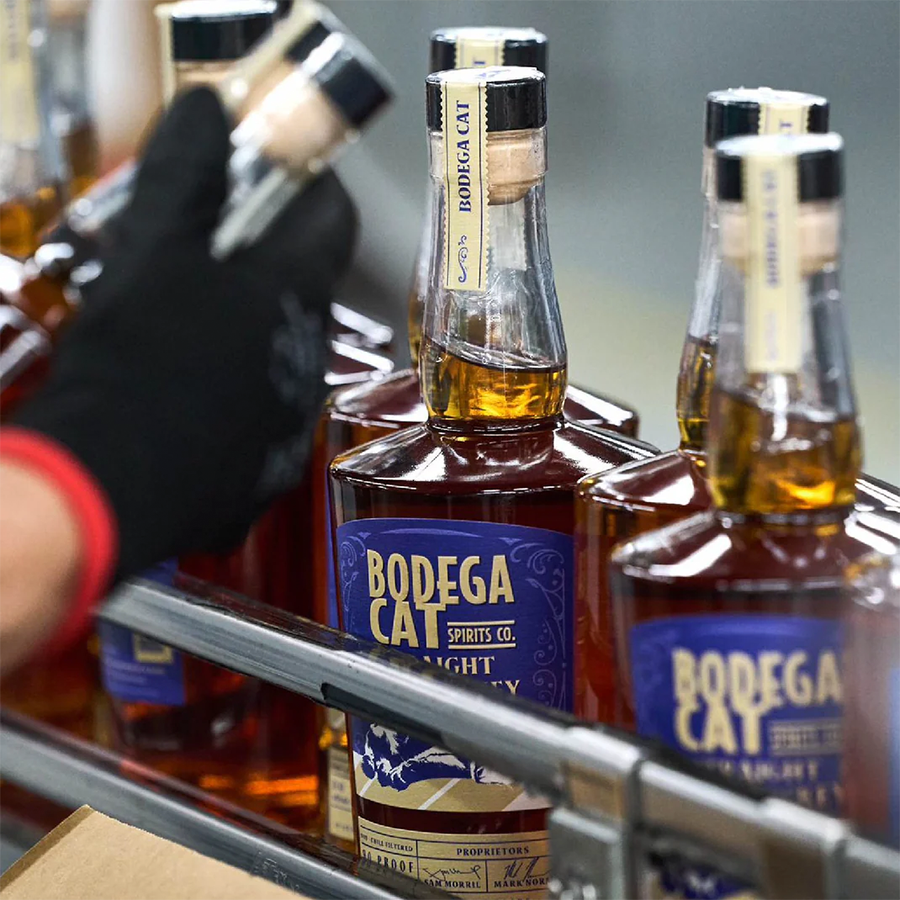 Bodega Cat Straight Rye whiskey bottles being packaged in a production facility.