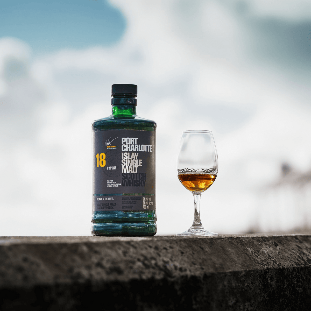 Port Charlotte 18 Year Islay Single Malt Scotch Whisky bottle with a tasting glass against a blurred background.