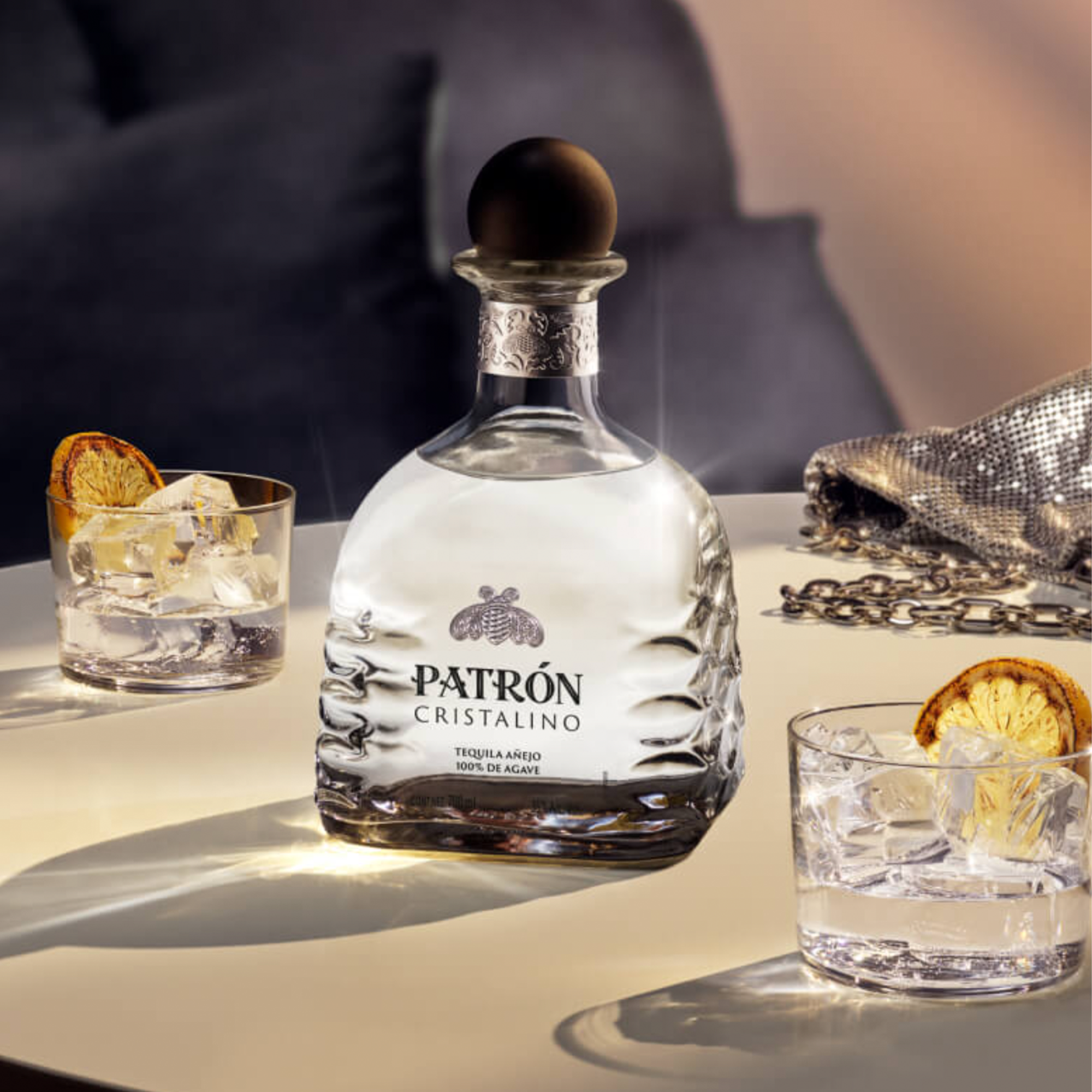 Patrón Cristalino Añejo Tequila bottle with glasses of tequila and ice, showcasing its premium quality and elegance.