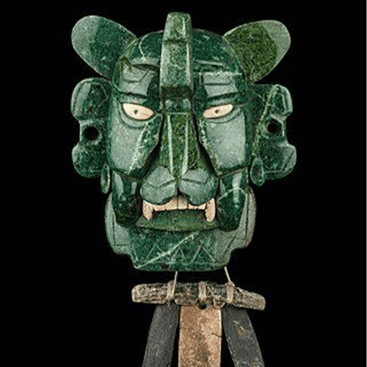 Ancient jade mask depicting a jaguar, showcasing intricate carvings and expressive facial features.