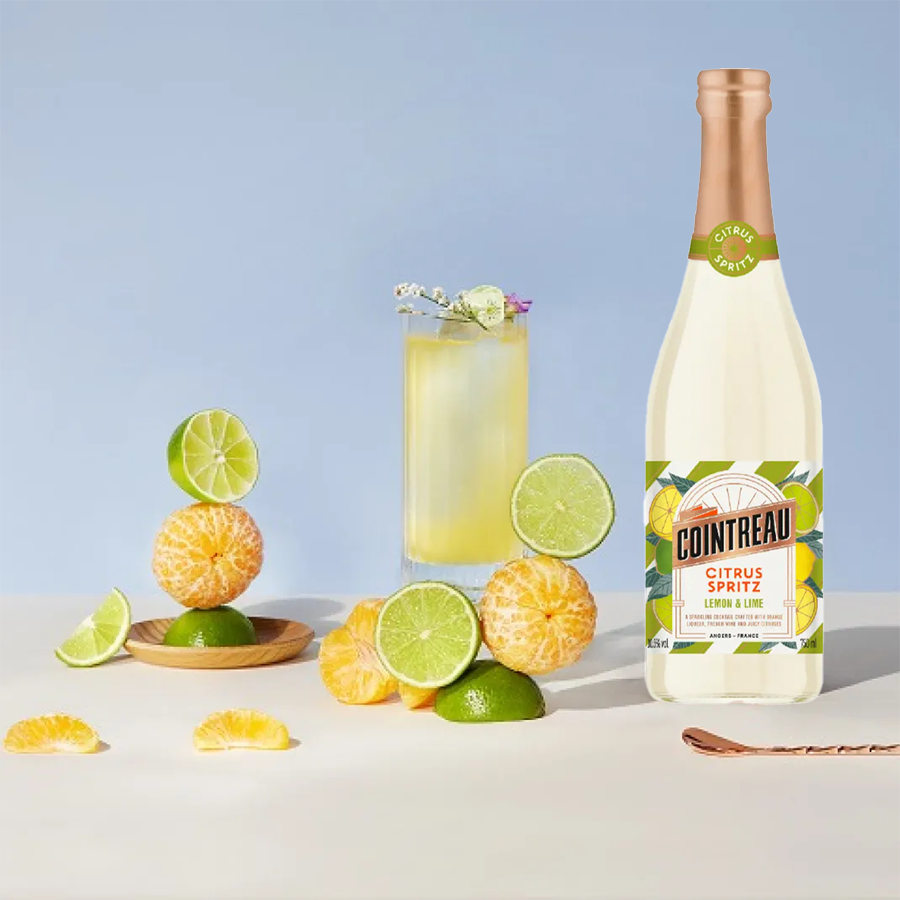 Cointreau Citrus Spritz Lemon & Lime bottle surrounded by citrus fruits and a refreshing cocktail.