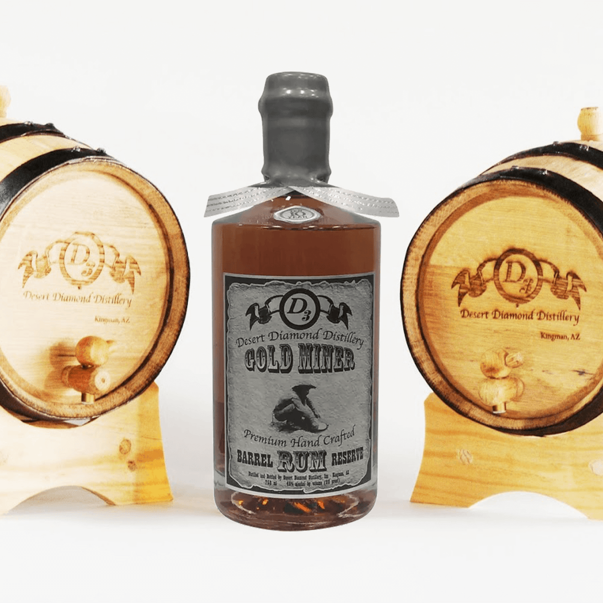 Desert Diamond Gold Miner Platinum Rum bottle with two oak barrels, showcasing Arizona's premium craft distilling.