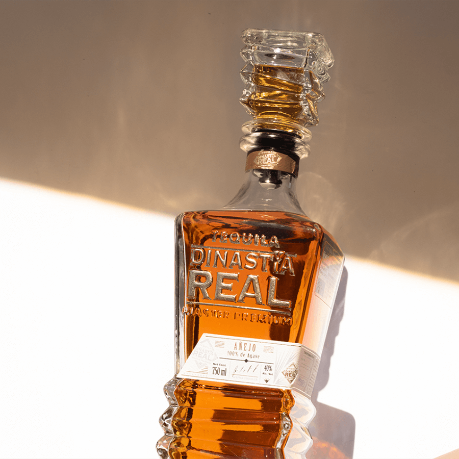 Bottle of Dinastía Real Añejo Tequila showcasing its rich amber color and unique design.