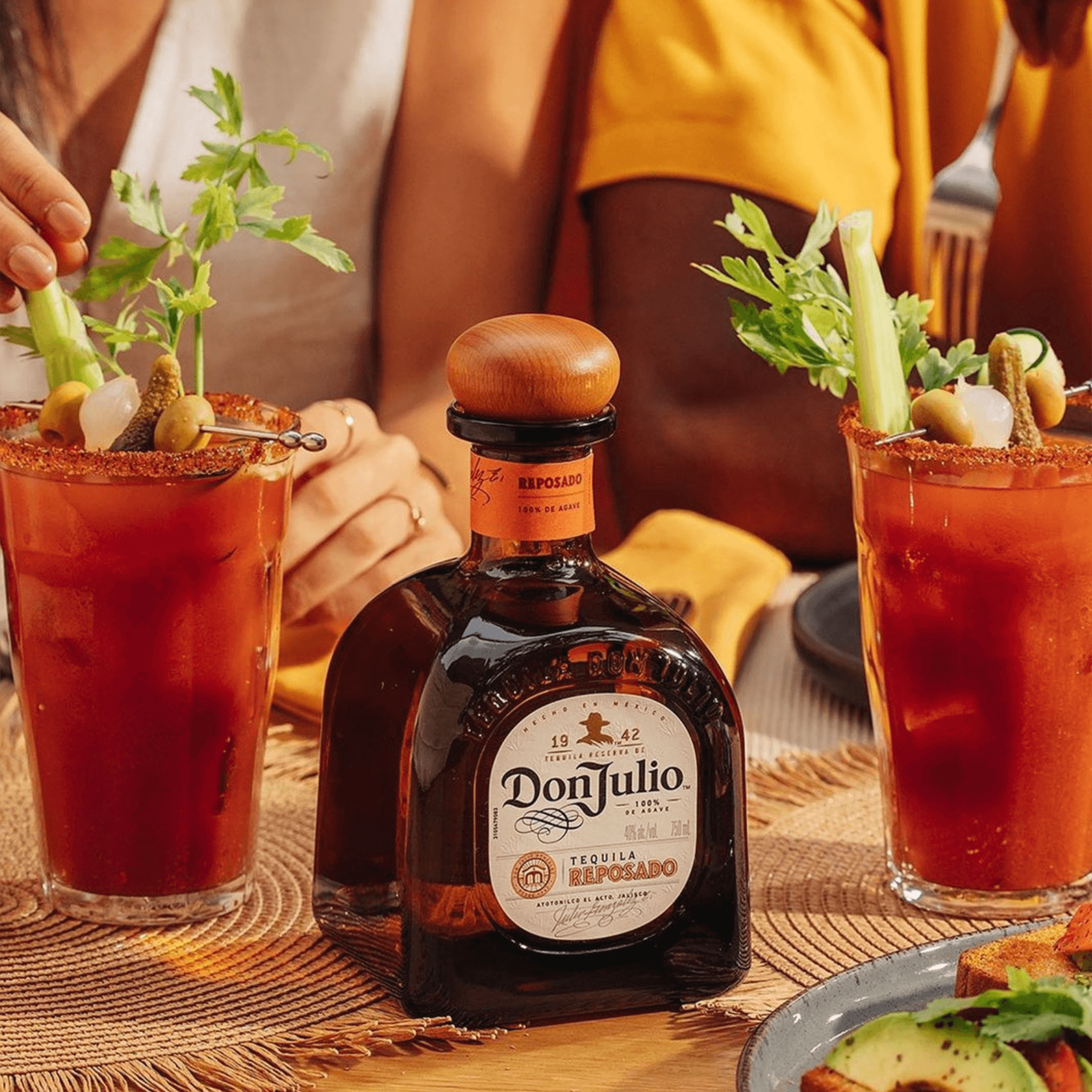 Don Julio Reposado Tequila bottle surrounded by brunch cocktails garnished with celery and olives.