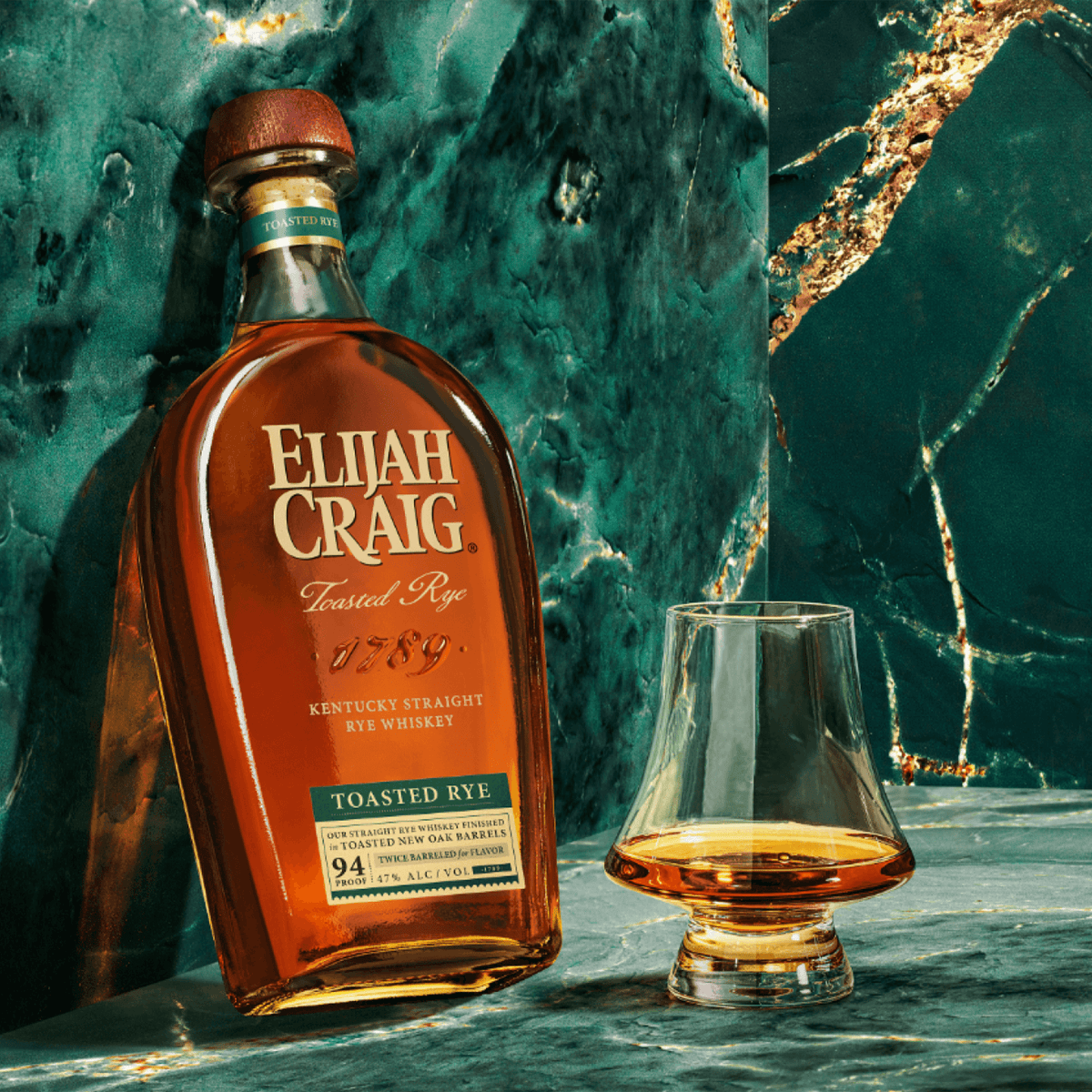 Elijah Craig Toasted Rye Whiskey bottle next to a glass of whiskey, highlighting its rich color and luxurious packaging.