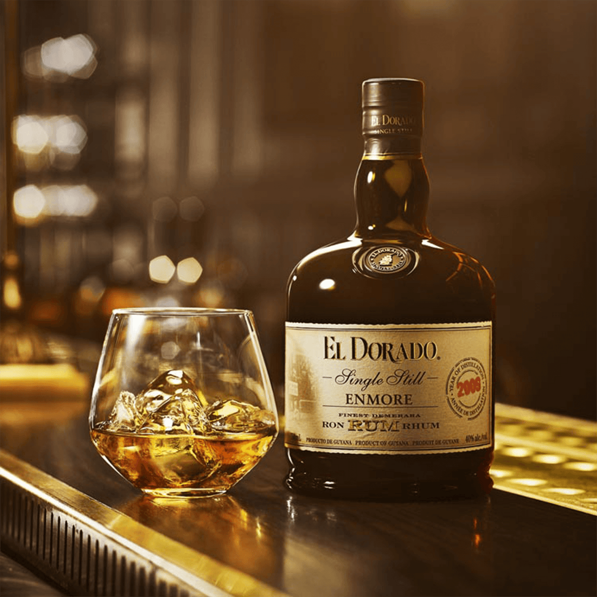 El Dorado Single Still Enmore Rum bottle beside a glass of rum with ice on a bar countertop.
