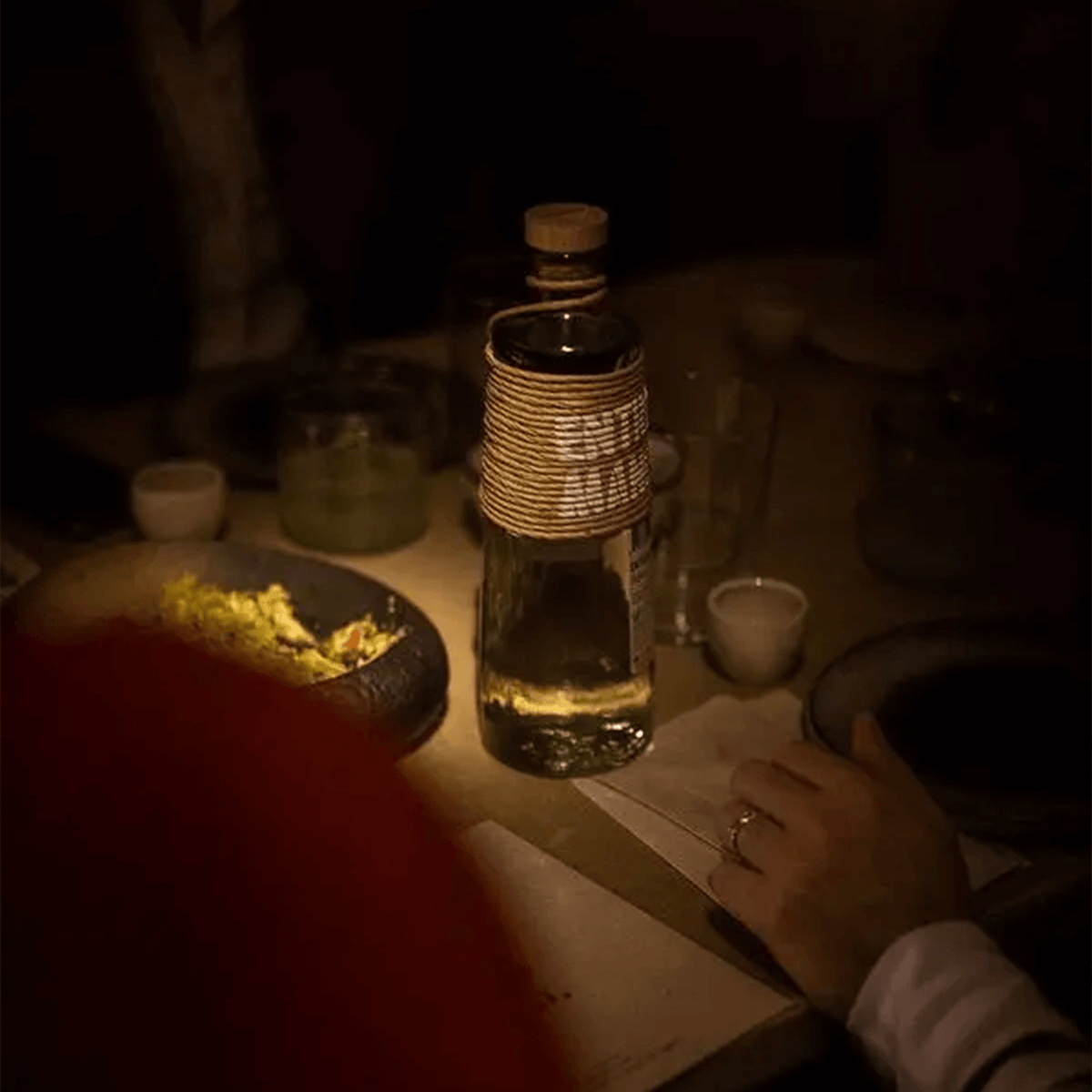 Bottle of Entremanos Blanco Tequila 700ml illuminated at a dining table with food and drinks, creating a cozy atmosphere.