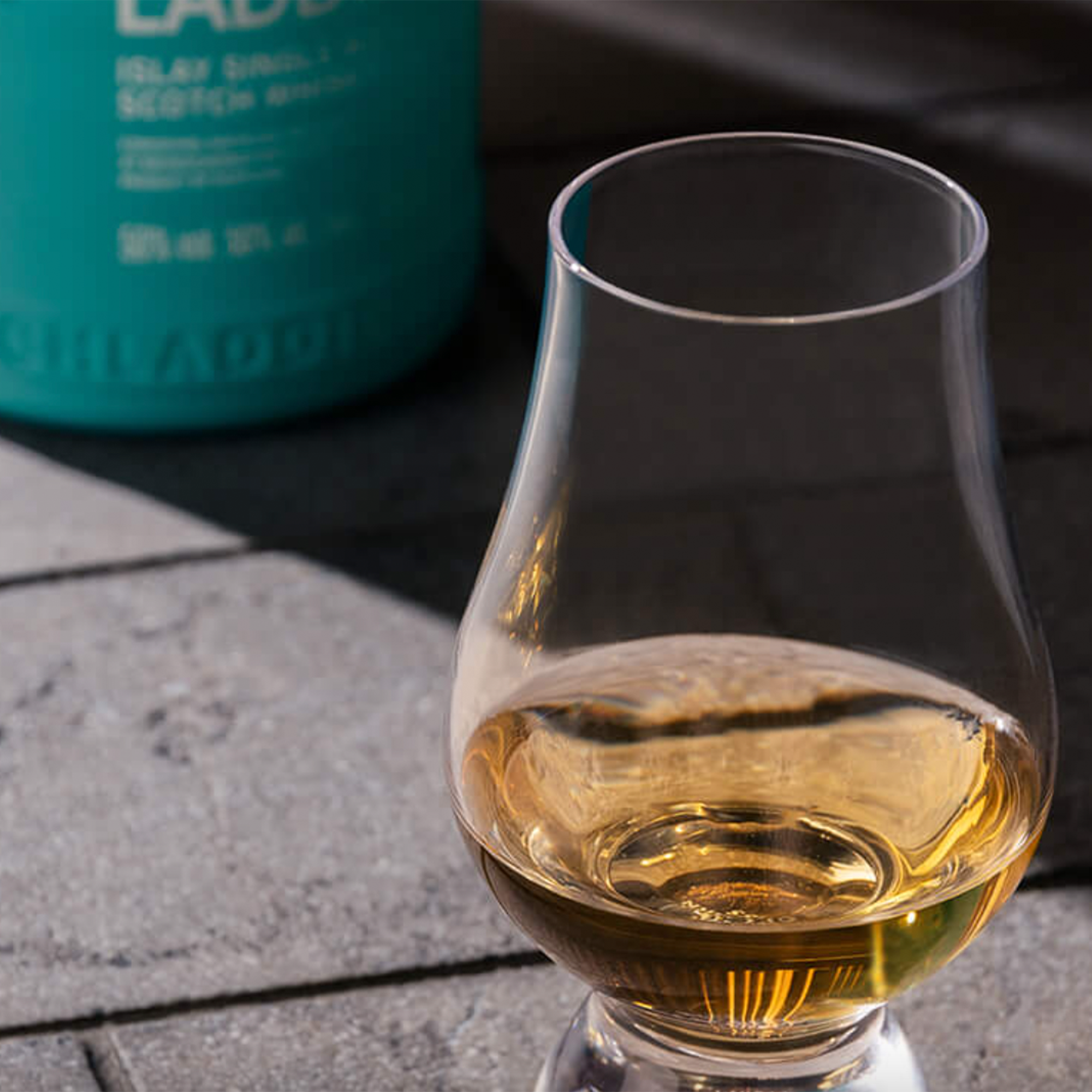 Glass of Bruichladdich Bere Barley 2013 Single Malt Scotch on a stone surface.