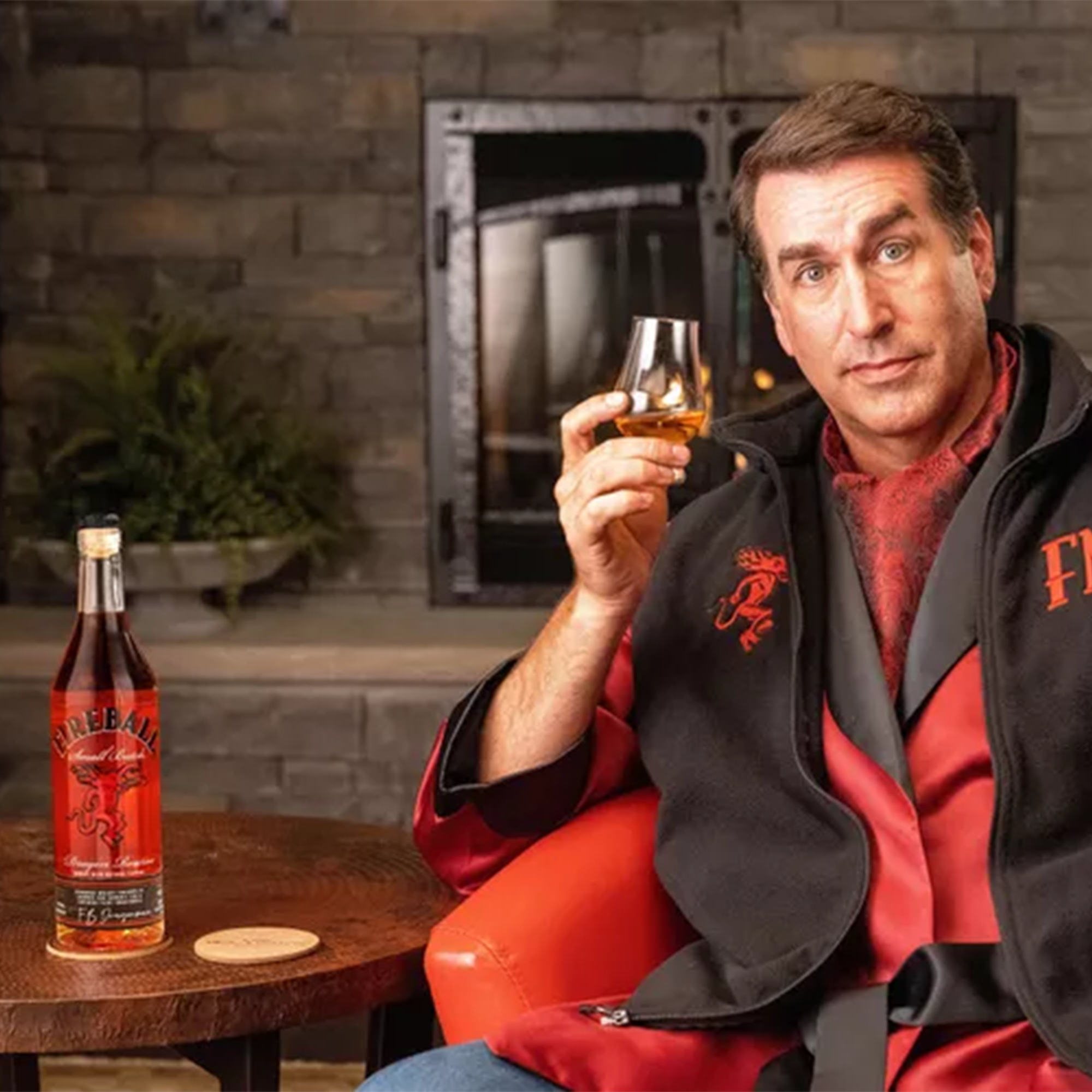 Man in a cozy setting enjoying Fireball Dragon Reserve Small Batch Whisky beside the fireplace.