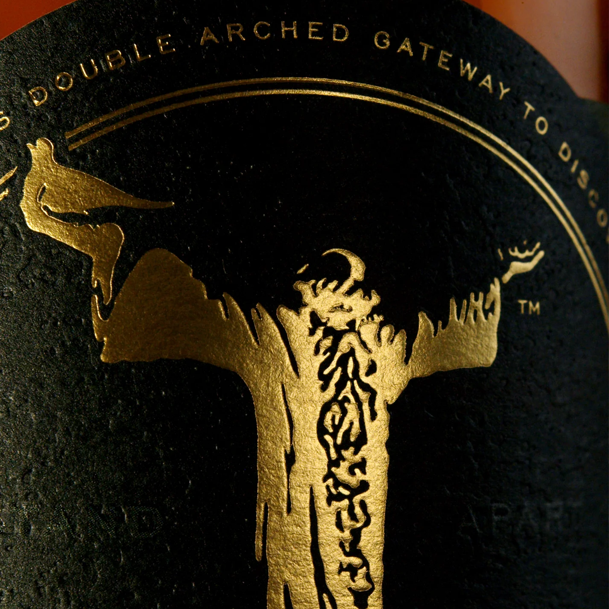 Close-up of the Glendalough Irish Whiskey label featuring a golden illustration of a figure with outstretched arms.