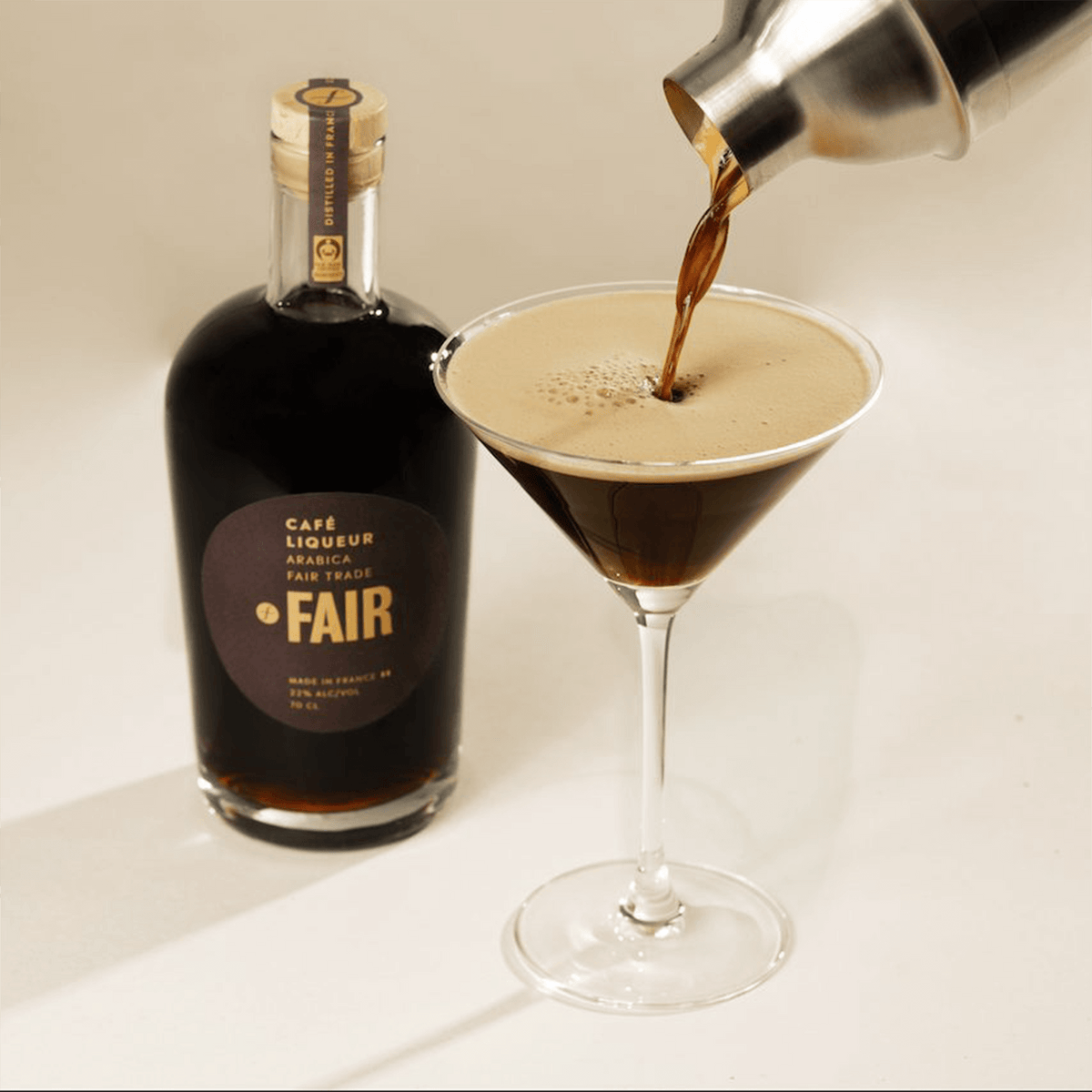 Pouring Fair Café Liqueur into a martini glass, showcasing roasted coffee aroma and rich flavors.