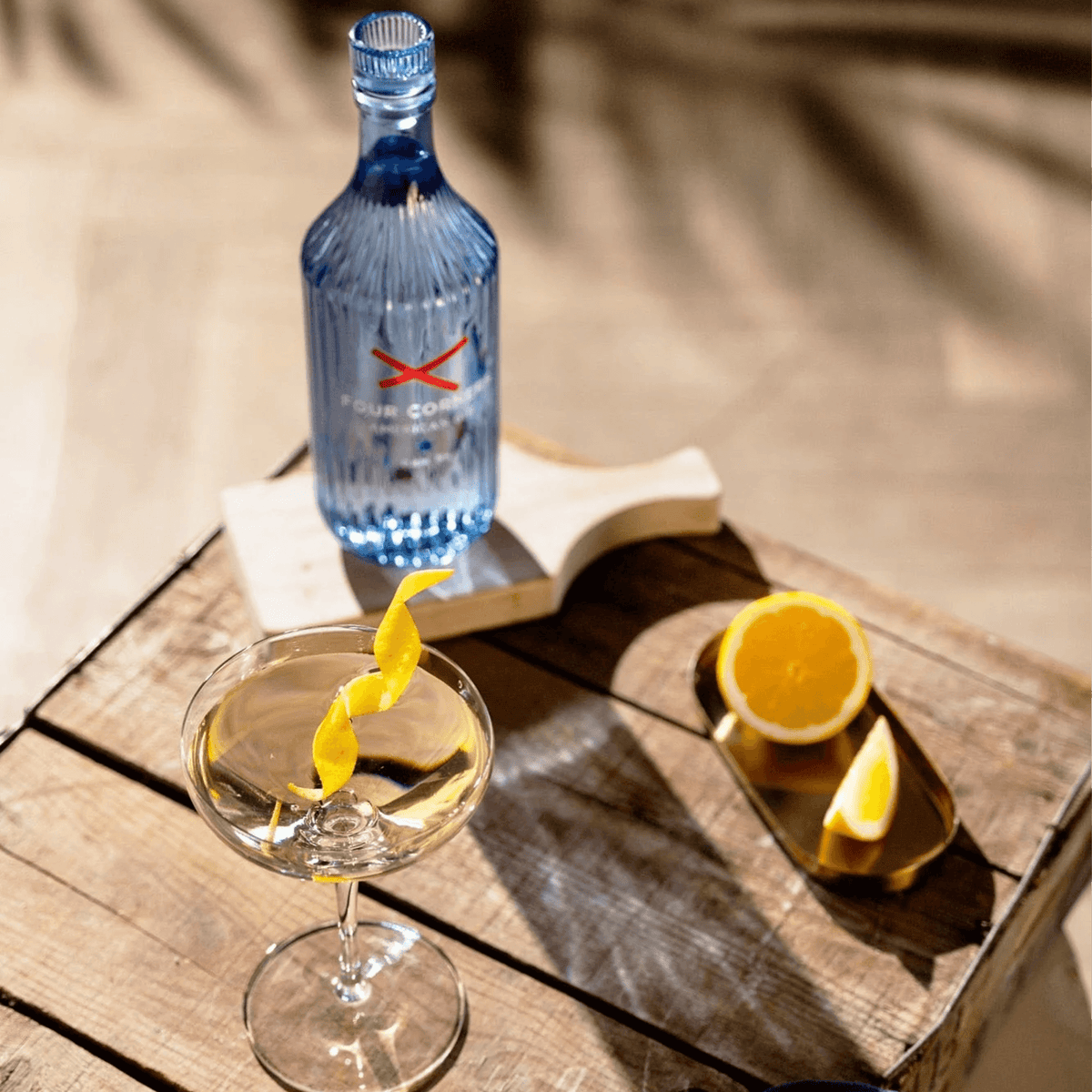 Four Corners American Gin bottle with a cocktail and fresh citrus on a wooden table.