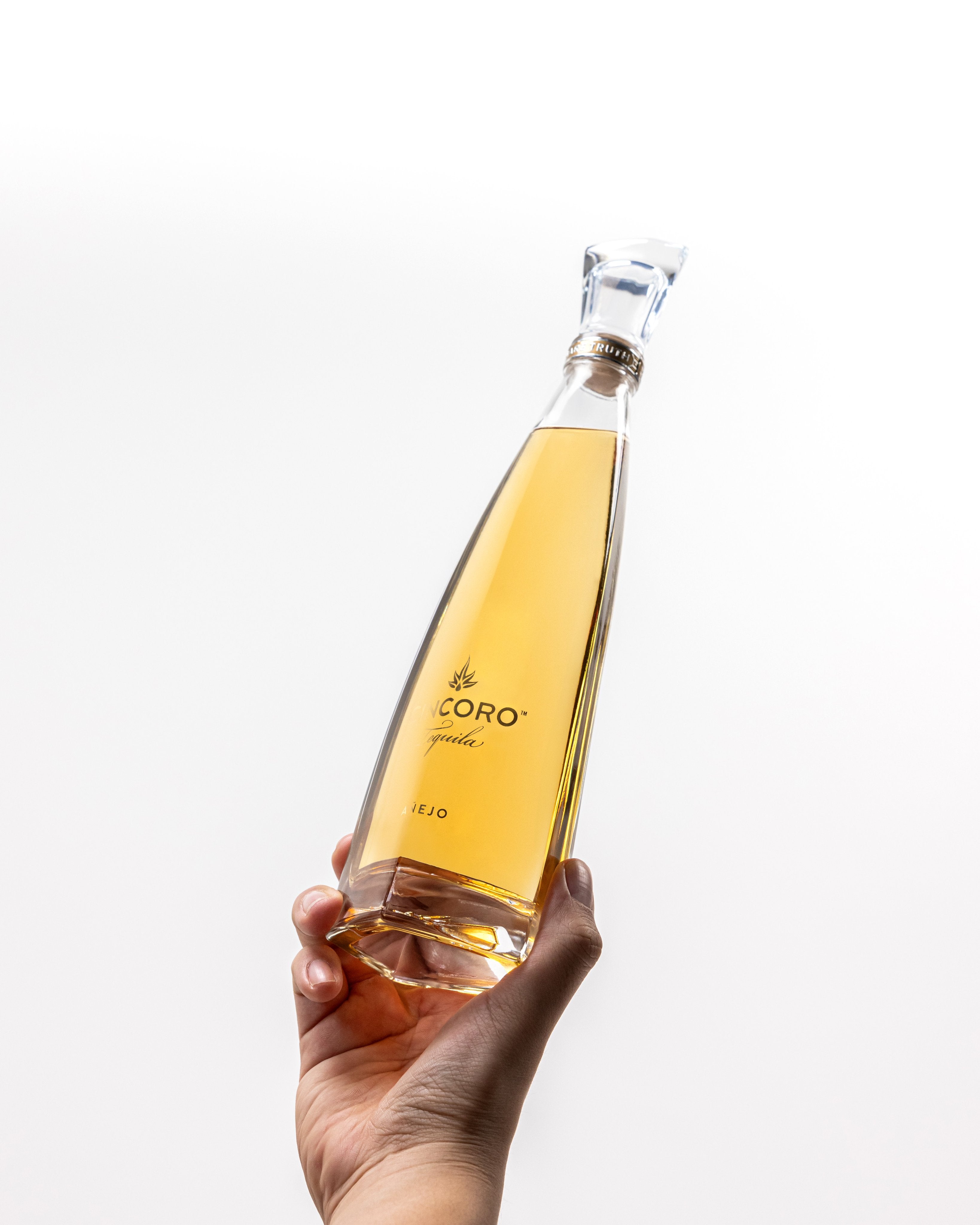 Cincoro Añejo Tequila 375mL bottle held in hand, showcasing its amber color and elegant design.