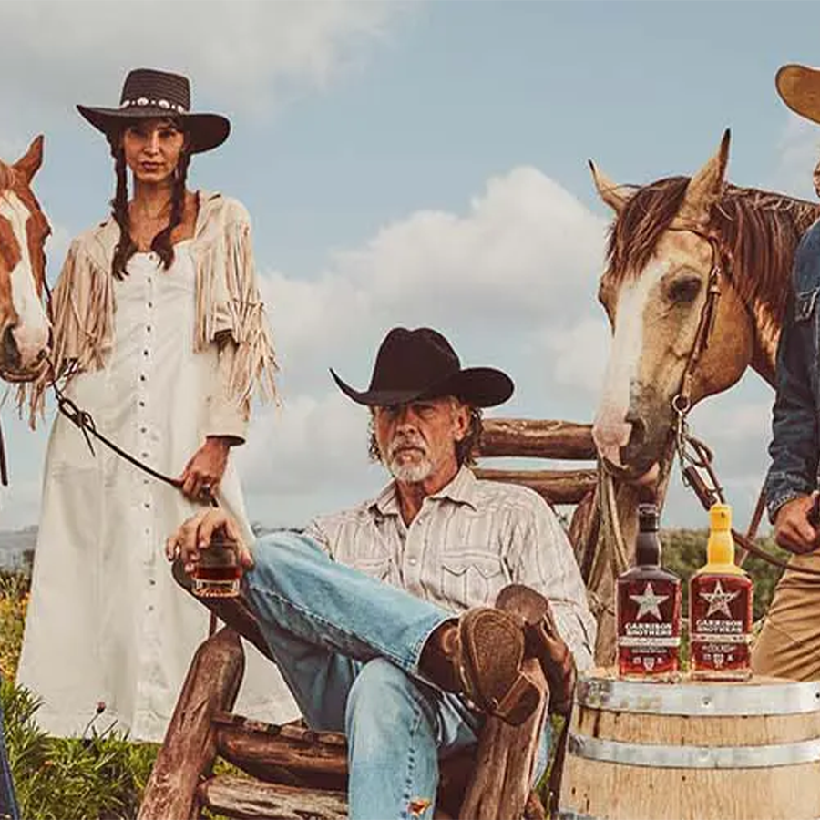 Group of people celebrating Garrison Brothers Boot Straight Bourbon Whiskey with horses in a Texas landscape.
