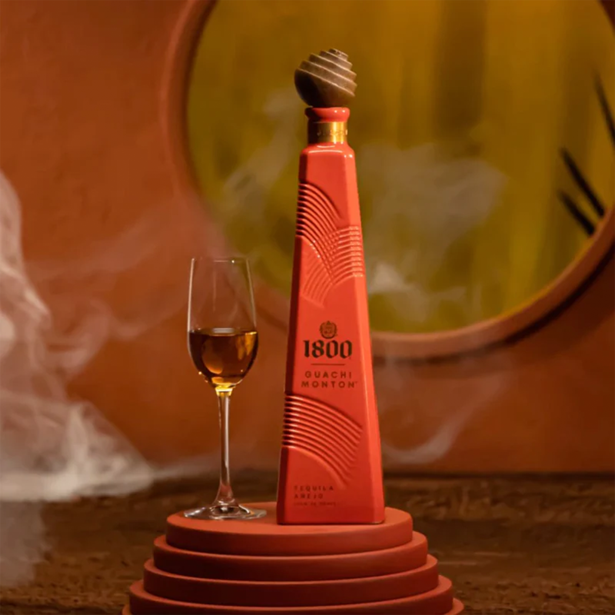 1800 Guachi Monton Añejo Tequila bottle with a glass, showcasing rich amber color and elegant design.
