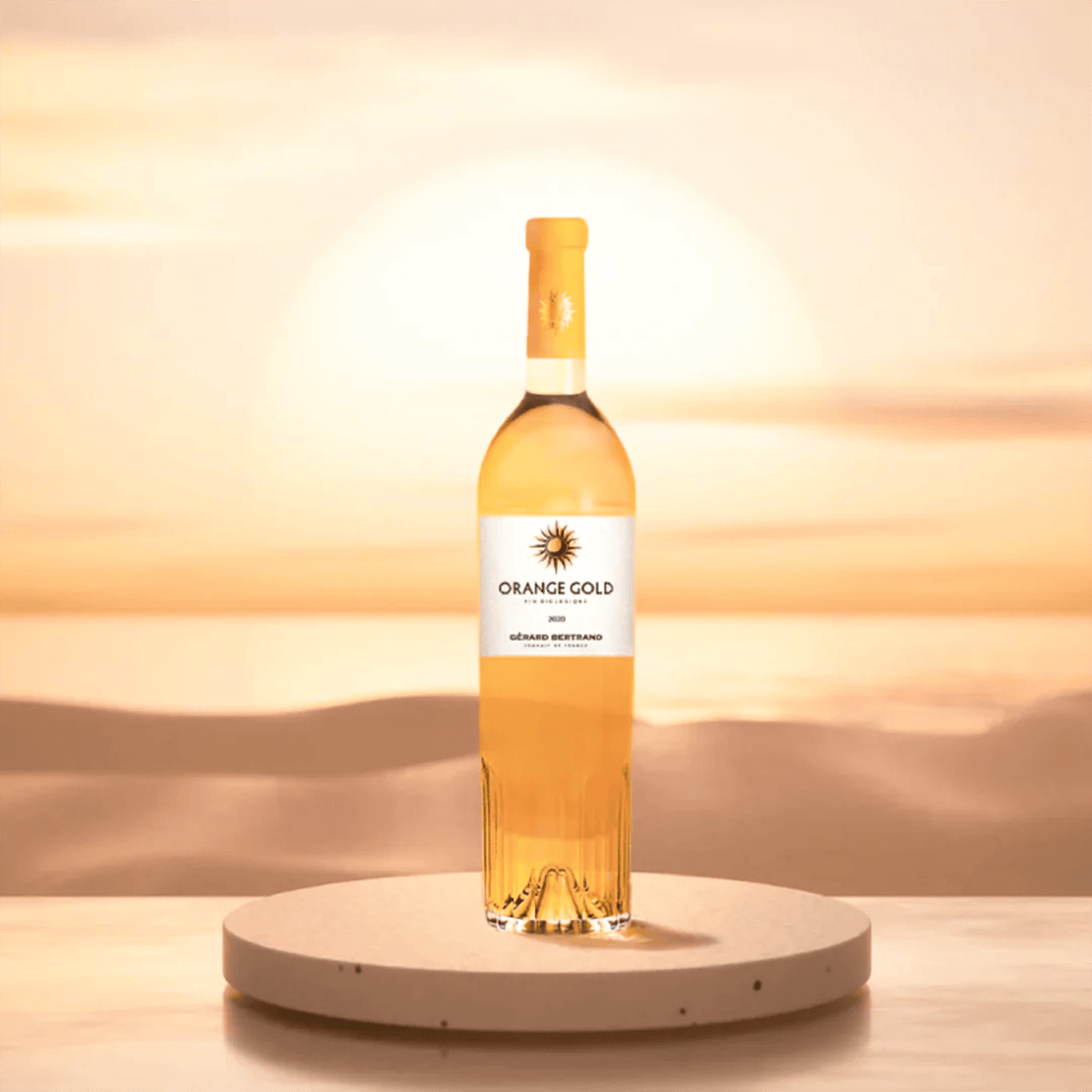 Bottle of Gérard Bertrand Orange Gold wine against a sunset backdrop, showcasing its vibrant orange hue.
