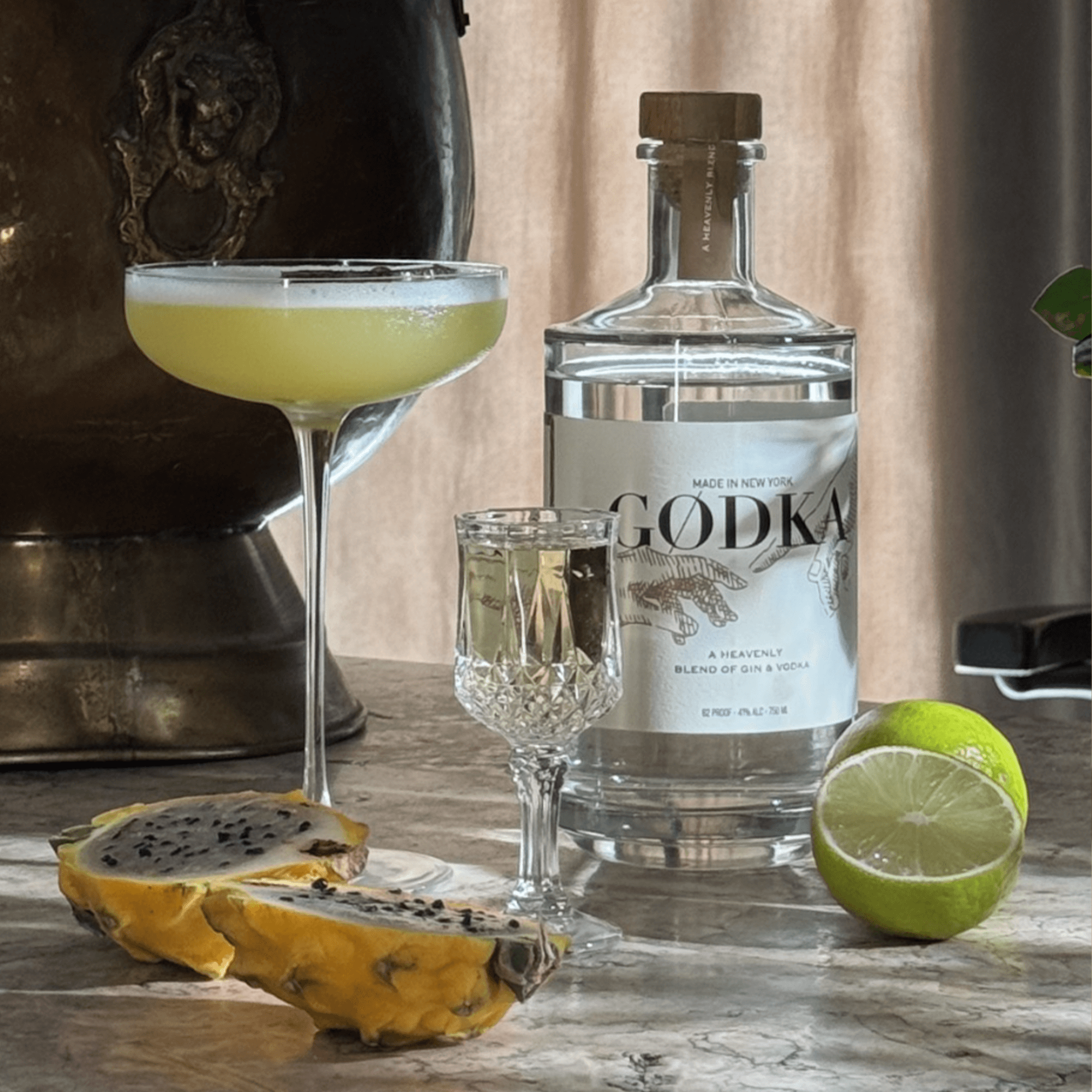GODKA gin and vodka blend bottle with cocktails and tropical fruit on a marble countertop.