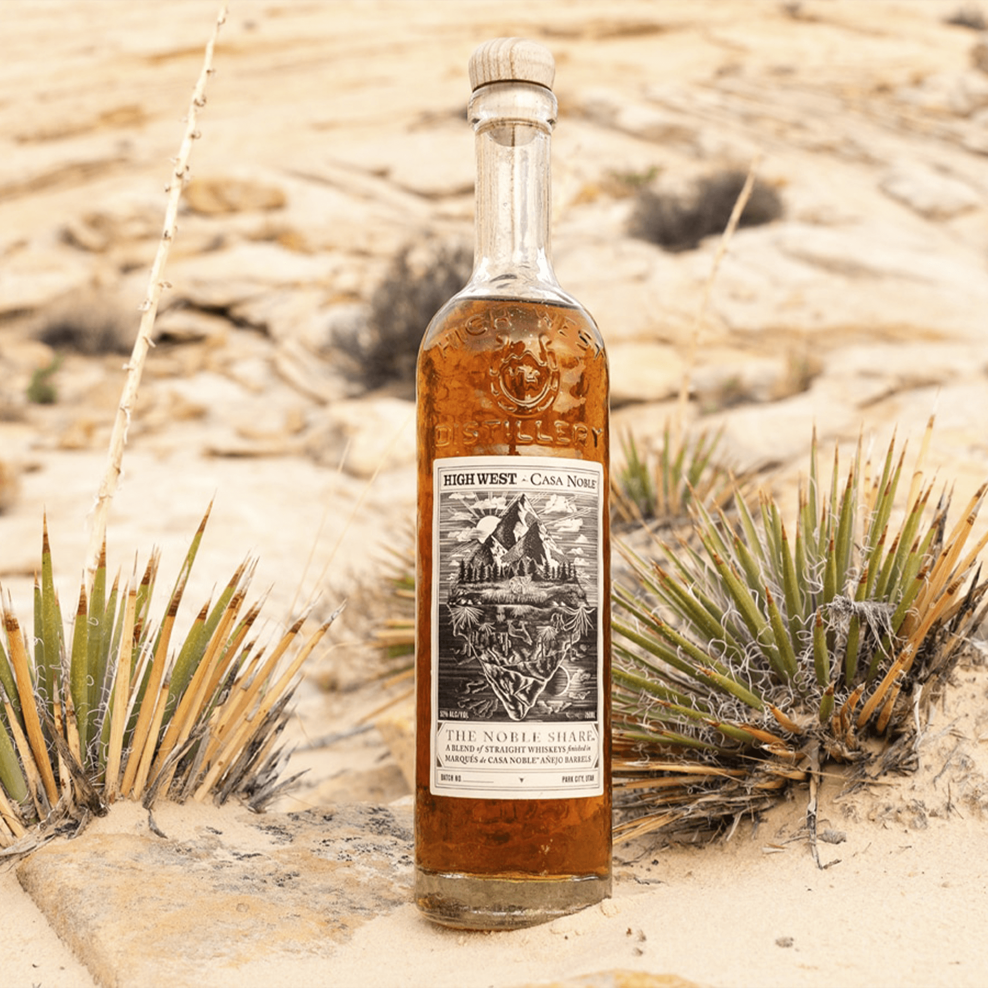 High West x Casa Noble The Noble Share Whiskey bottle in a desert setting, showcasing its unique blend and branding.