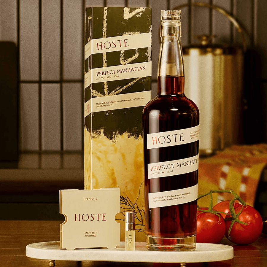 Hoste Perfect Manhattan Cocktail with bottle, vermouth, and bitters on a wooden surface, showcasing a sophisticated cocktail experience.