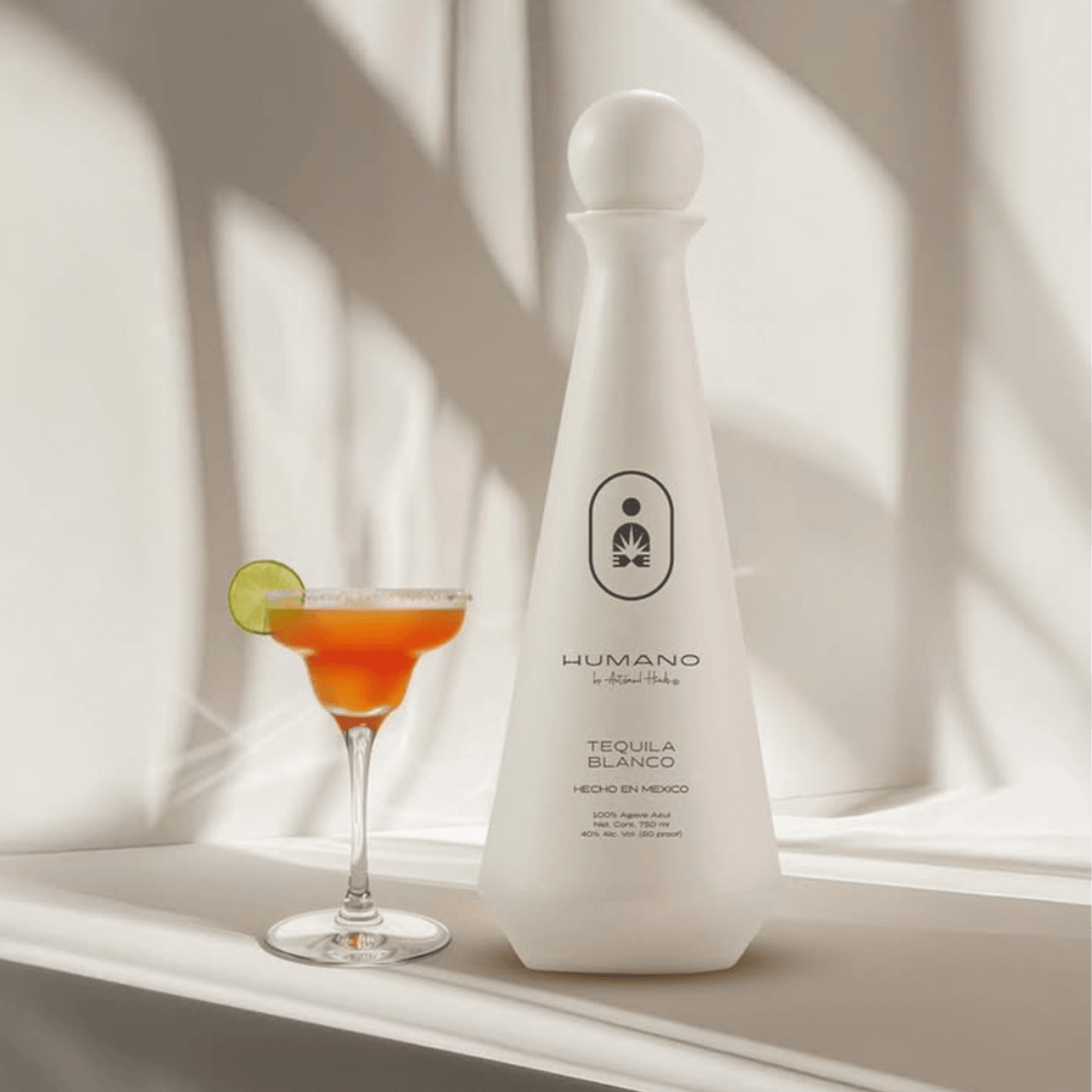 Humano Blanco Tequila bottle with a citrus cocktail on a stylish surface, showcasing a fresh and vibrant presentation.