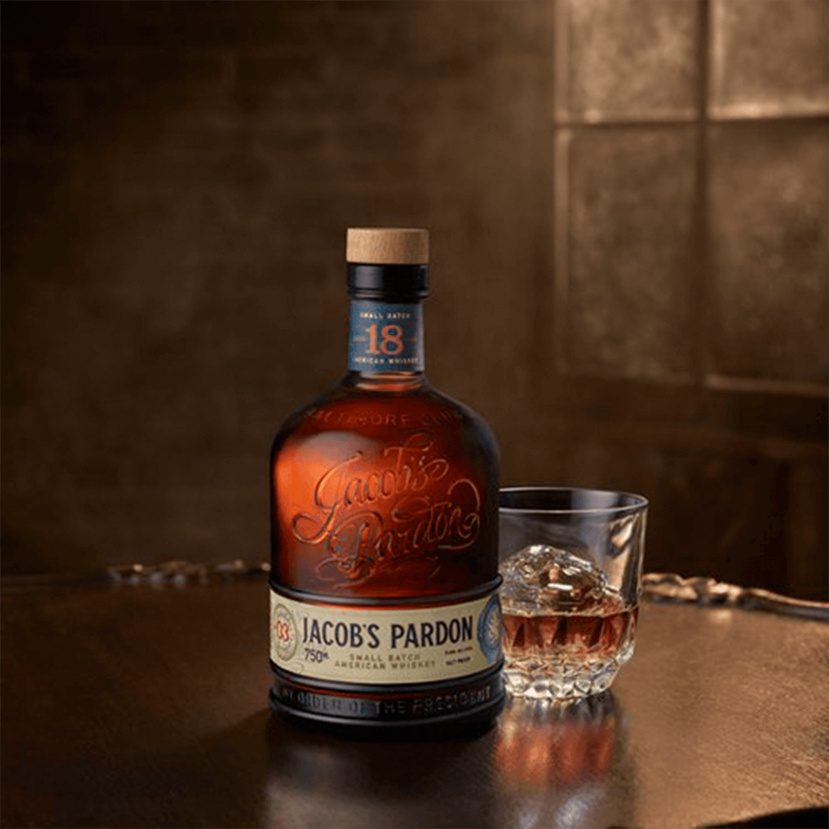 Bottle of Jacob's Pardon Small Batch No 3 American Whiskey with a glass of whiskey on a wooden table.