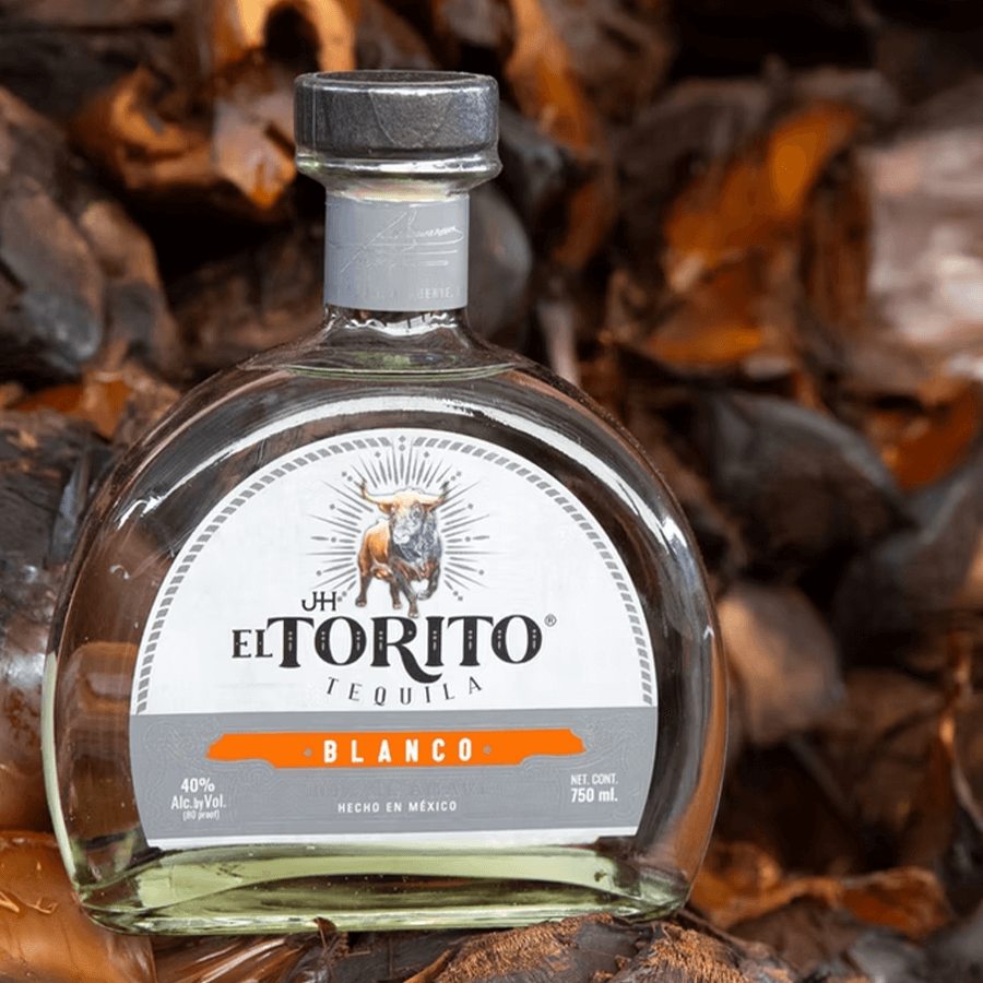 Bottle of JH El Torito Blanco Tequila set against agave plant background, showcasing artisanal craftsmanship.