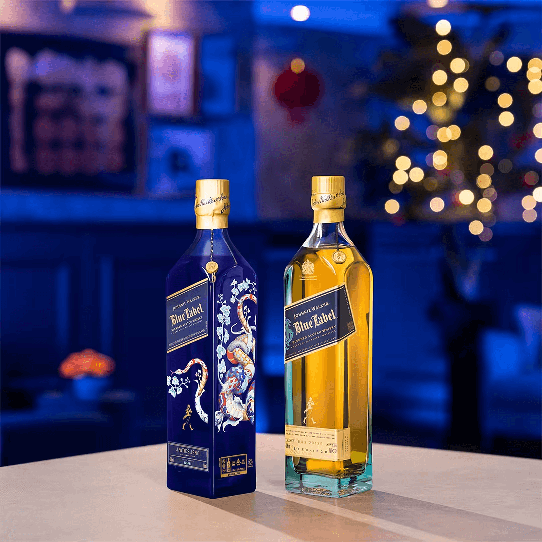 Two bottles of Johnnie Walker Blue Label Scotch, one limited edition Year of the Snake design, against a festive background.