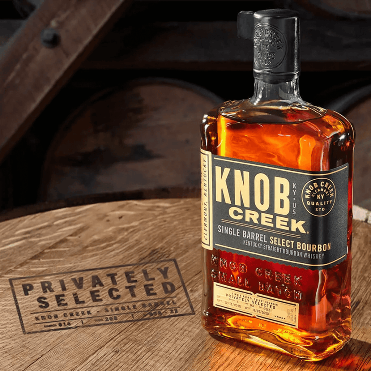 Knob Creek Cask Strength bourbon bottle on wooden barrel, showcasing exclusive private selection quality.