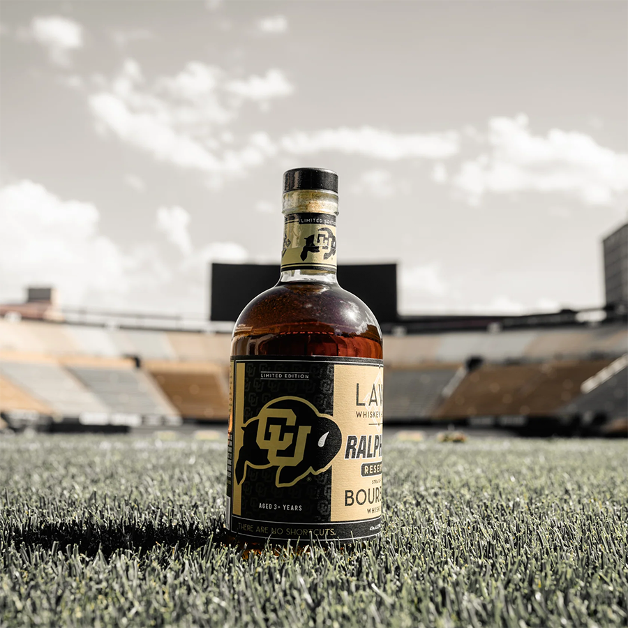 Laws Whiskey House Ralphie's Reserve Bourbon bottle on the field at a stadium, highlighting local Colorado heritage.