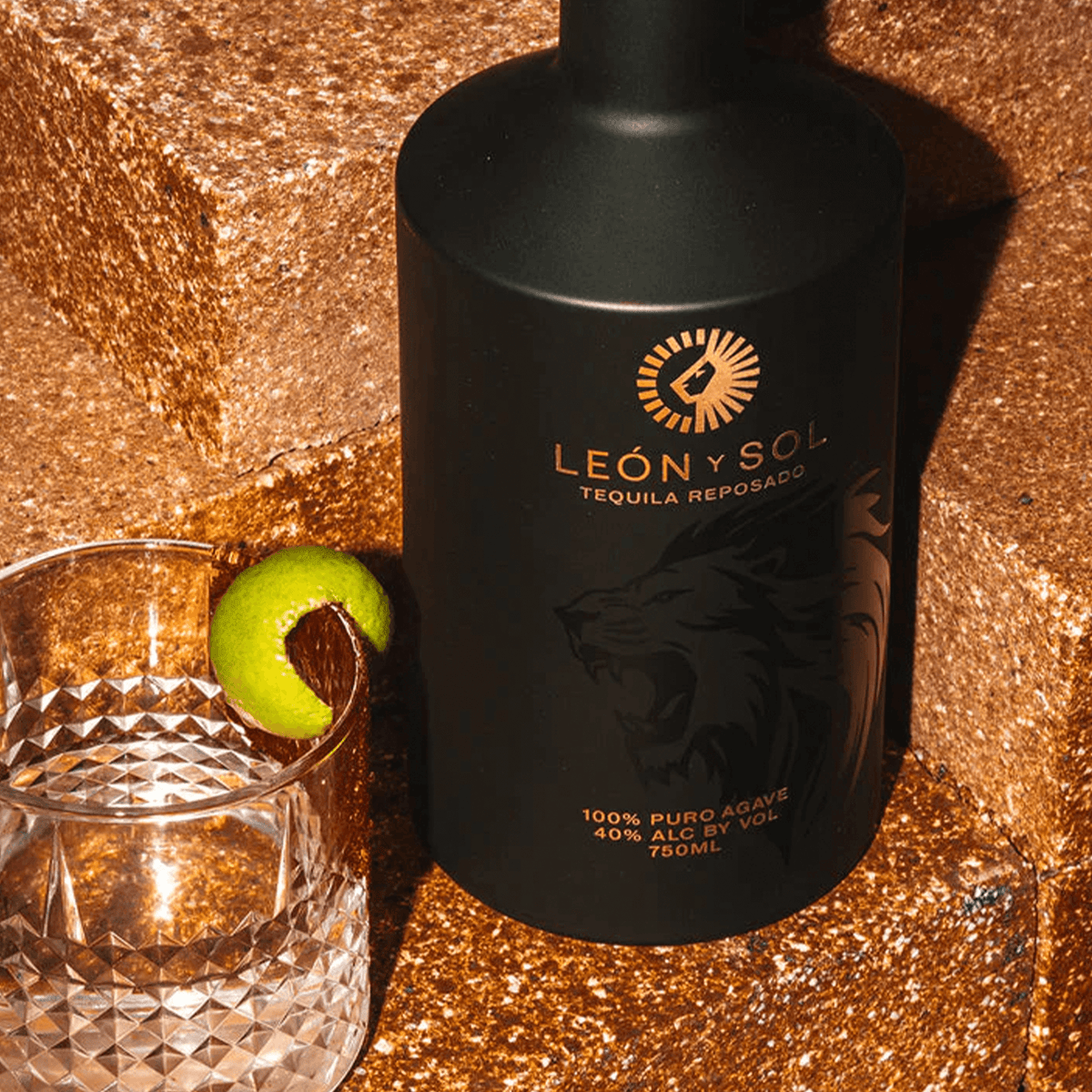 León y Sol Tequila Reposado bottle with lime garnish on textured background, 100% puro agave, 750ml.