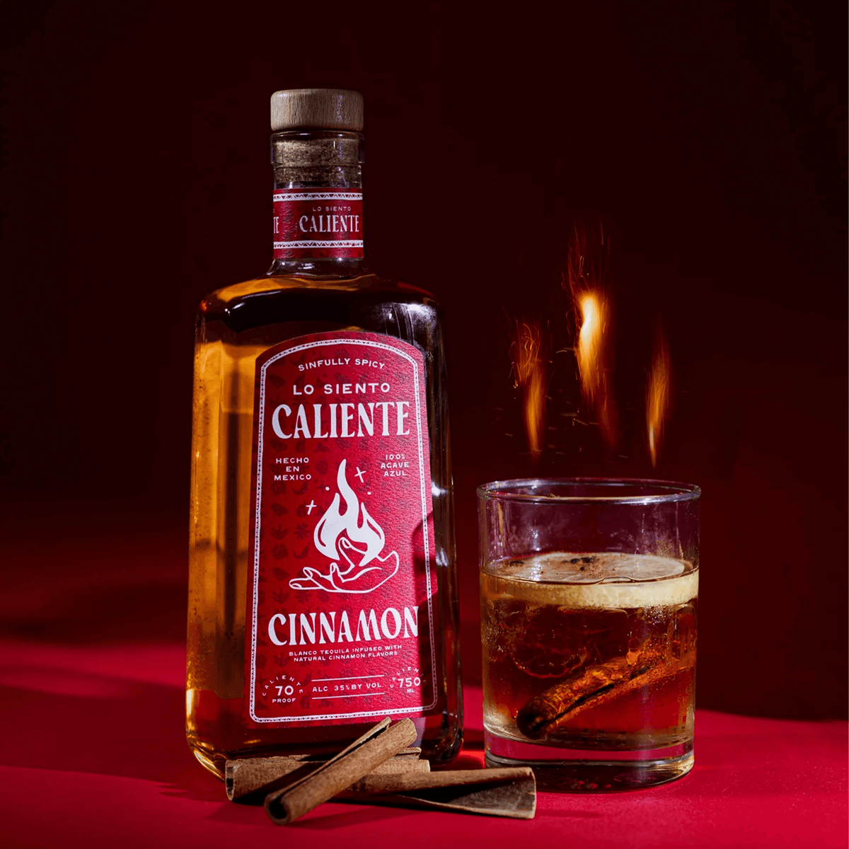 Lo Siento Caliente Cinnamon Tequila bottle with a glass and cinnamon sticks, showcasing its bold flavor and vibrant design.