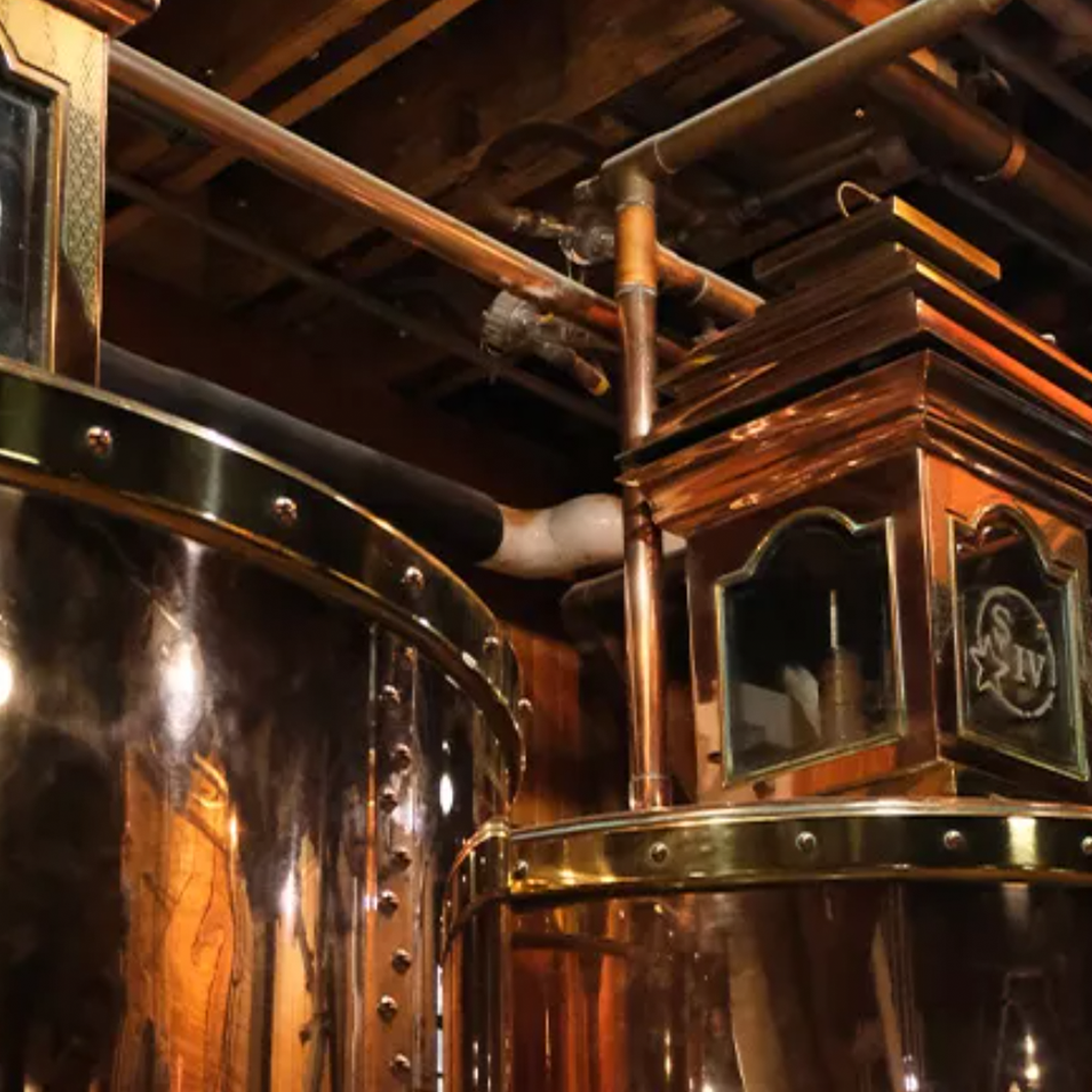 Maker's Mark distillery equipment featuring copper and stainless steel stills and intricate piping.